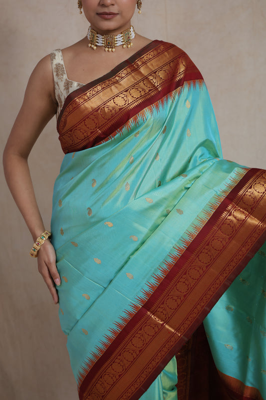 Mint green Gadwal silk saree with maroon zari border and intricate woven pallu, showcasing elegance and craftsmanship.