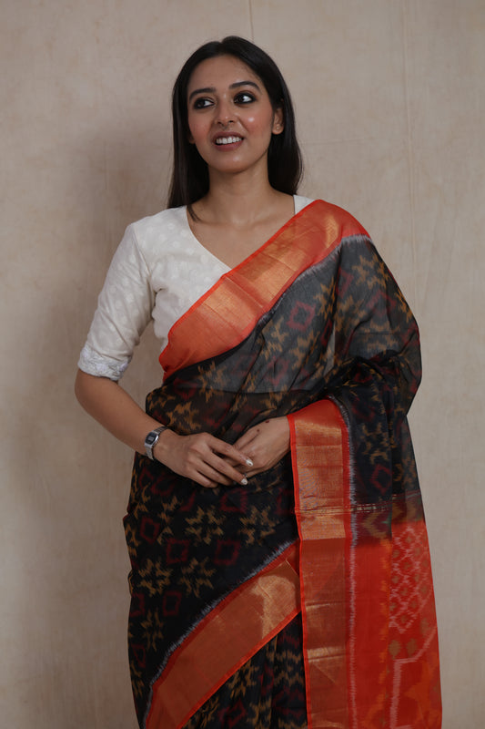 Close-up portrait showcasing black Panchampali SICO saree with vibrant orange woven border and pallu