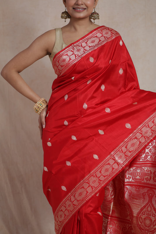 Close-up of the royal red Banarasi silk saree highlighting the finely woven buttas, floral border, and luxurious silk texture.