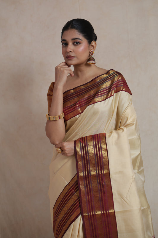 Close-up view of ivory Kanjivaram silk saree featuring maroon contrast border with intricate traditional weaving