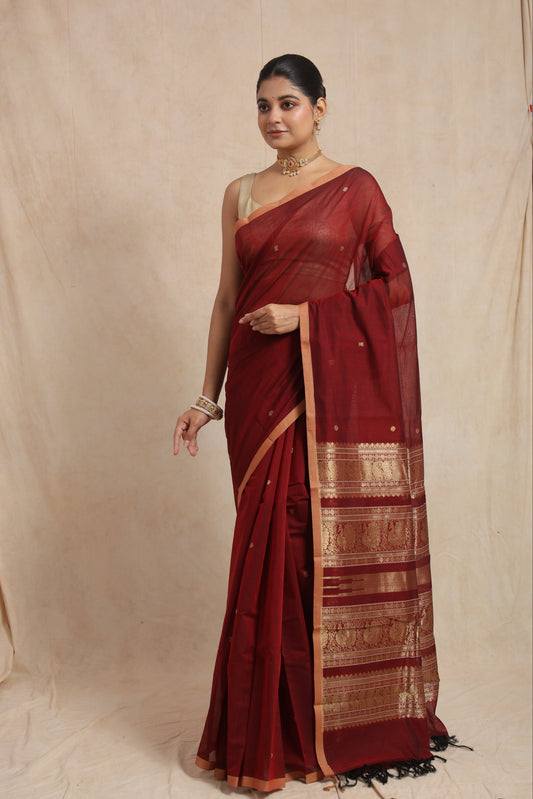 Front view of a maroon Kanchipuram cotton saree featuring delicate woven motifs, a copper-toned border, and a traditional pallu.
