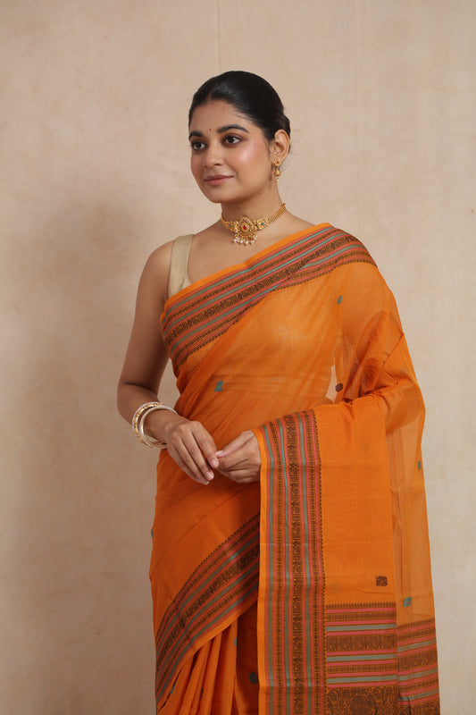 Close-up view of orange Kanchipuram cotton saree featuring delicate woven buttas and ethnic border