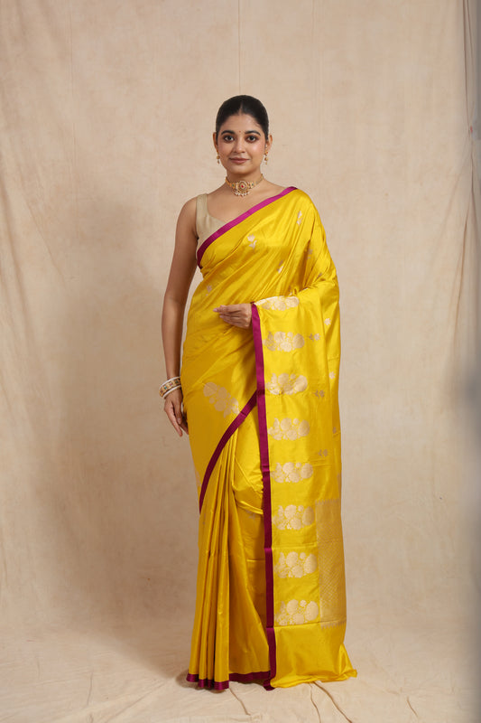 Model wearing sunshine yellow Banarasi silk saree with silver floral buttas