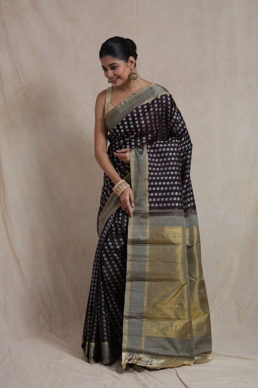 Deep espresso Kanjivaram silk saree with silver buttas and a rich gold pallu, shown from the back view.