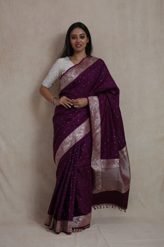 Model wearing deep wine Banarasi silk saree with silver zari buttas and woven border.