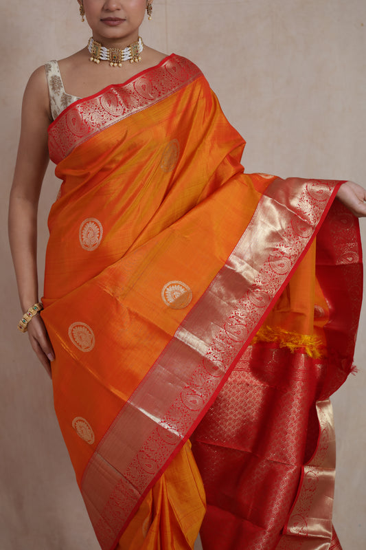 Festive orange Kanjivaram silk saree featuring traditional zari buttas