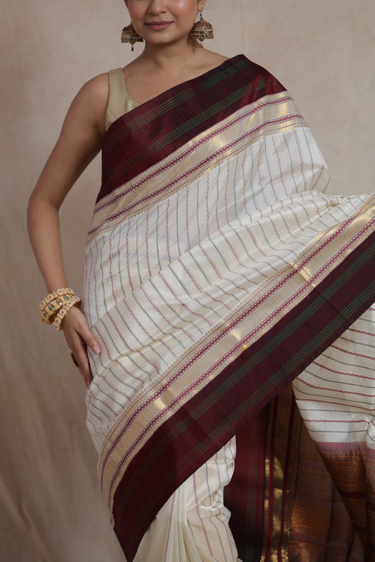 Close-up of maroon zari border on off white silk cotton saree