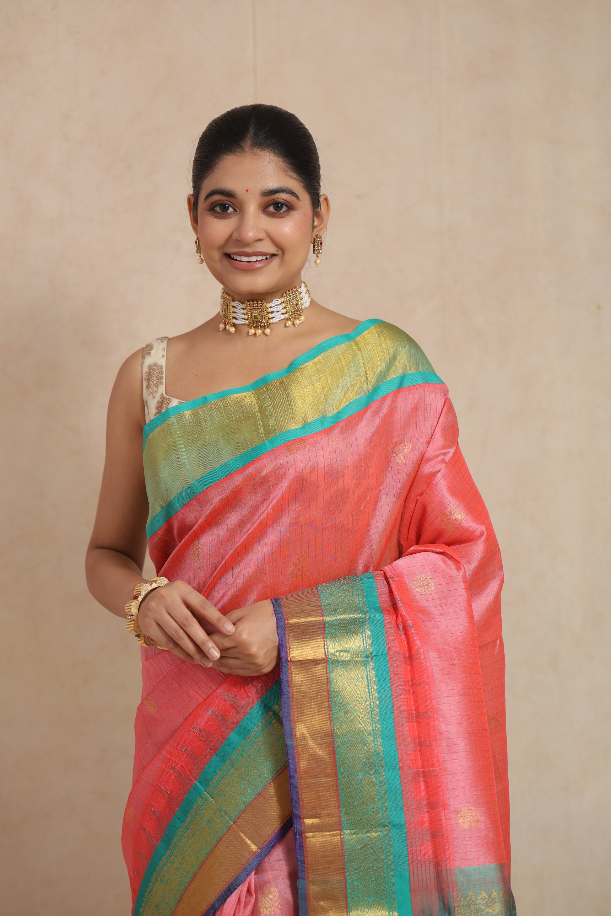 Close-up portrait of model wearing coral pink handloom SICO saree with traditional border