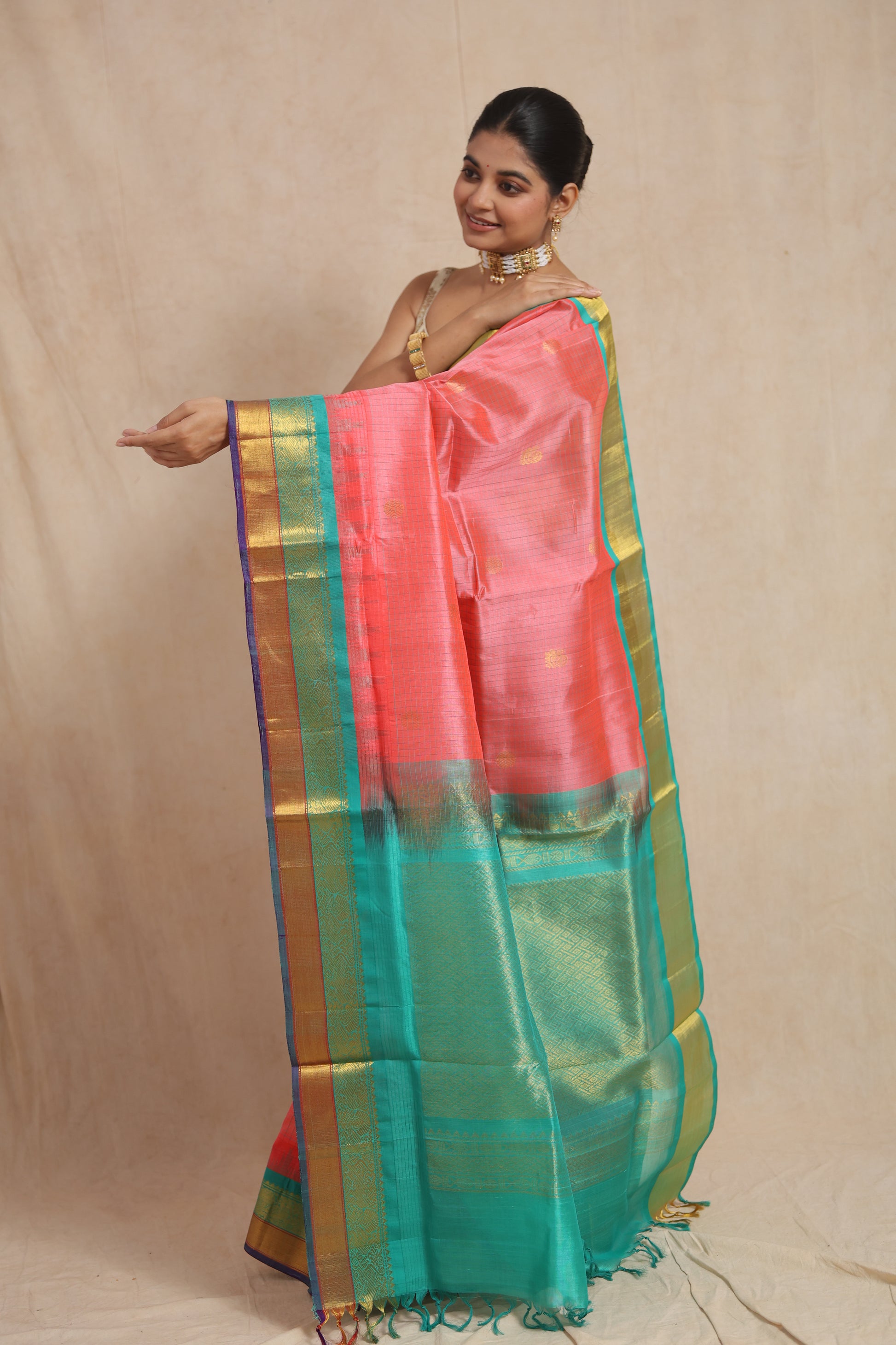 Detailed display of coral pink saree pallu with aqua green and gold woven border