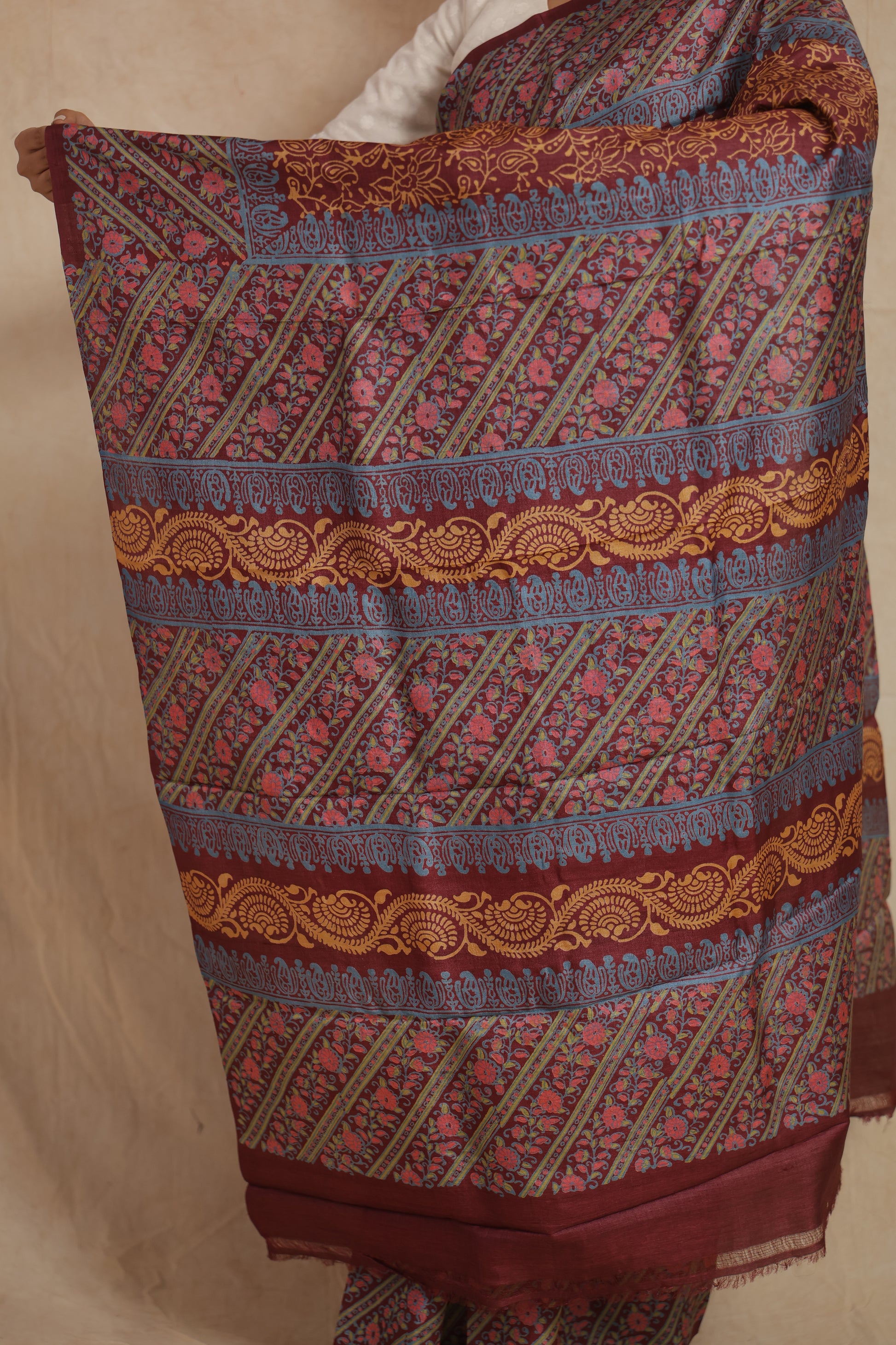 Portrait view of model wearing rust maroon printed Tussar silk saree