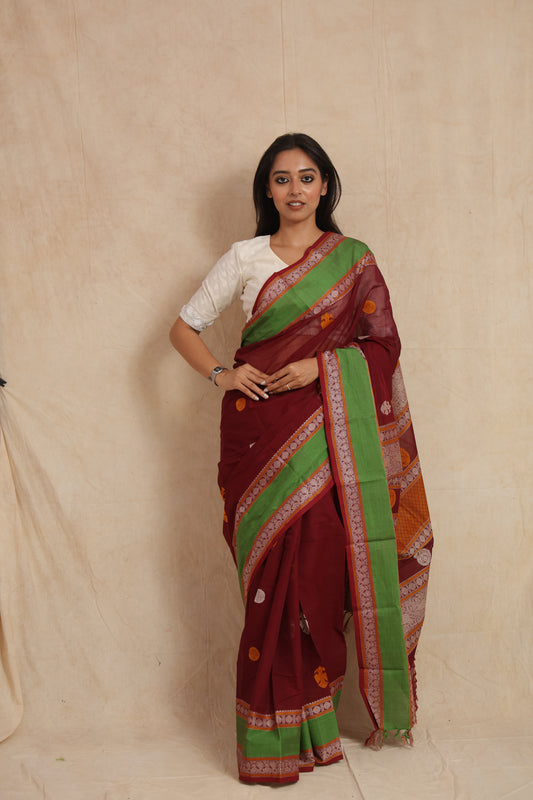 Front view of maroon Kanchipuram cotton saree with green border and traditional woven motifs