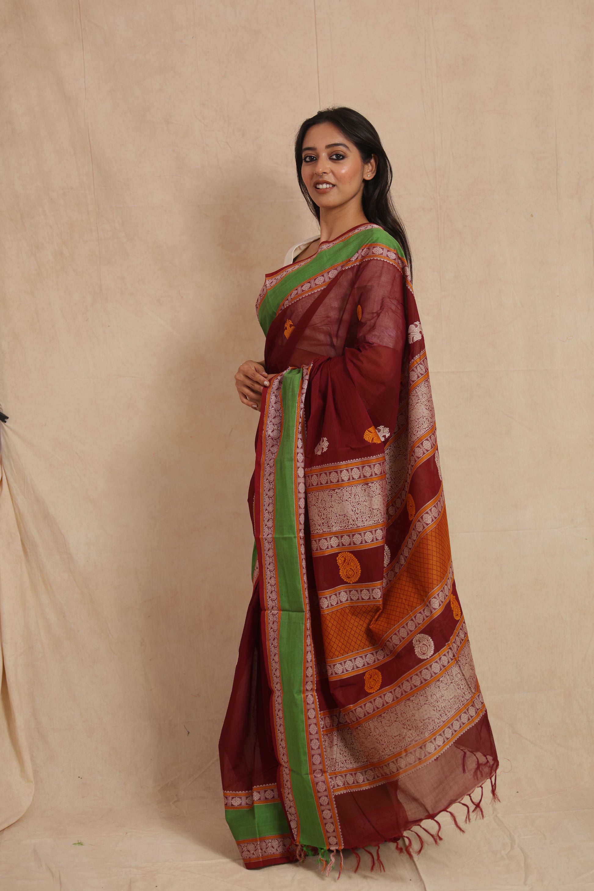 Side profile of maroon Kanchipuram cotton saree showcasing green border and elegant drape