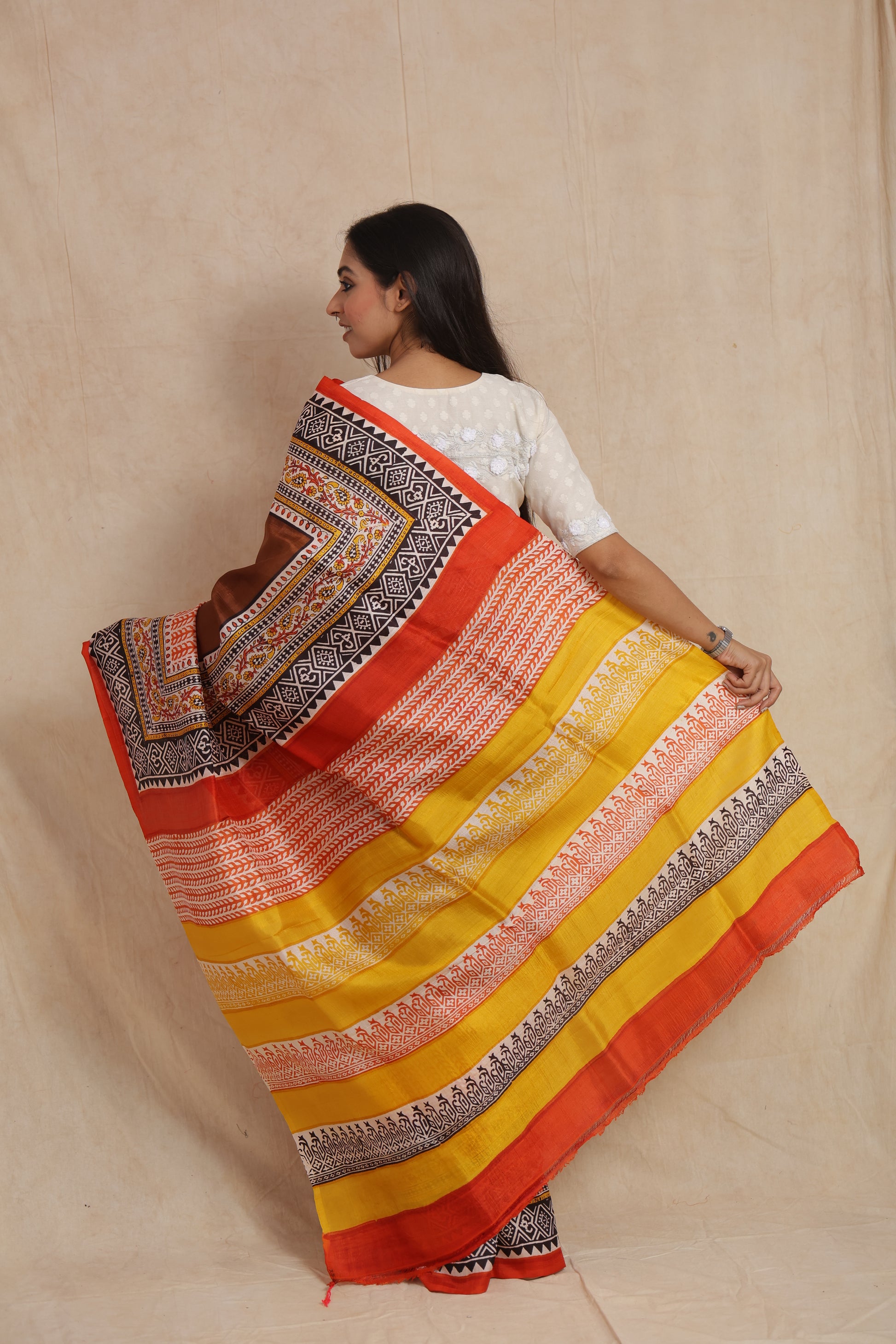 Back view showcasing the vibrant mustard yellow pallu with traditional Batik-inspired motifs