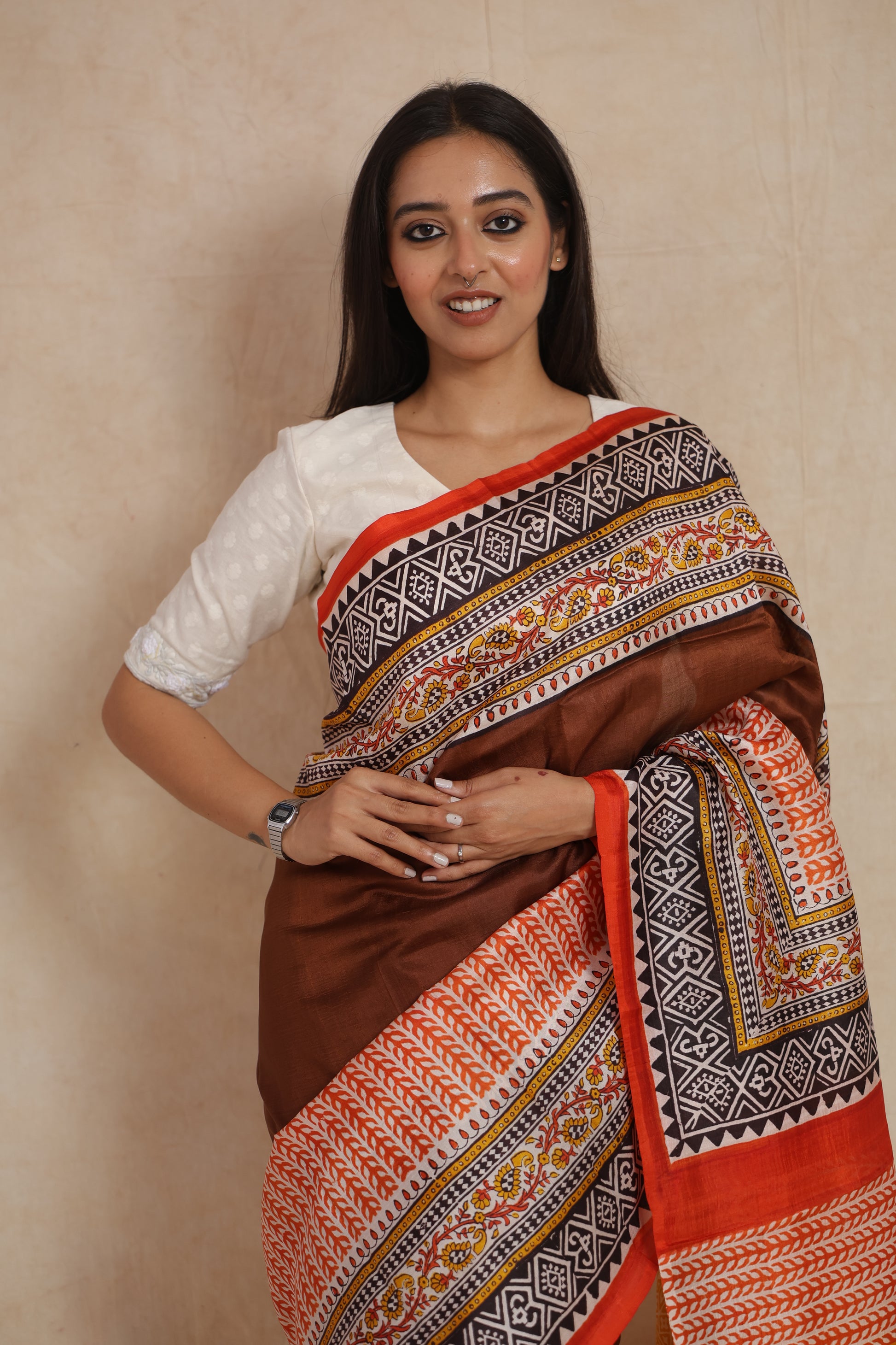 Detailed view of brown Batik silk saree with contrast orange border and decorative ethnic motifs