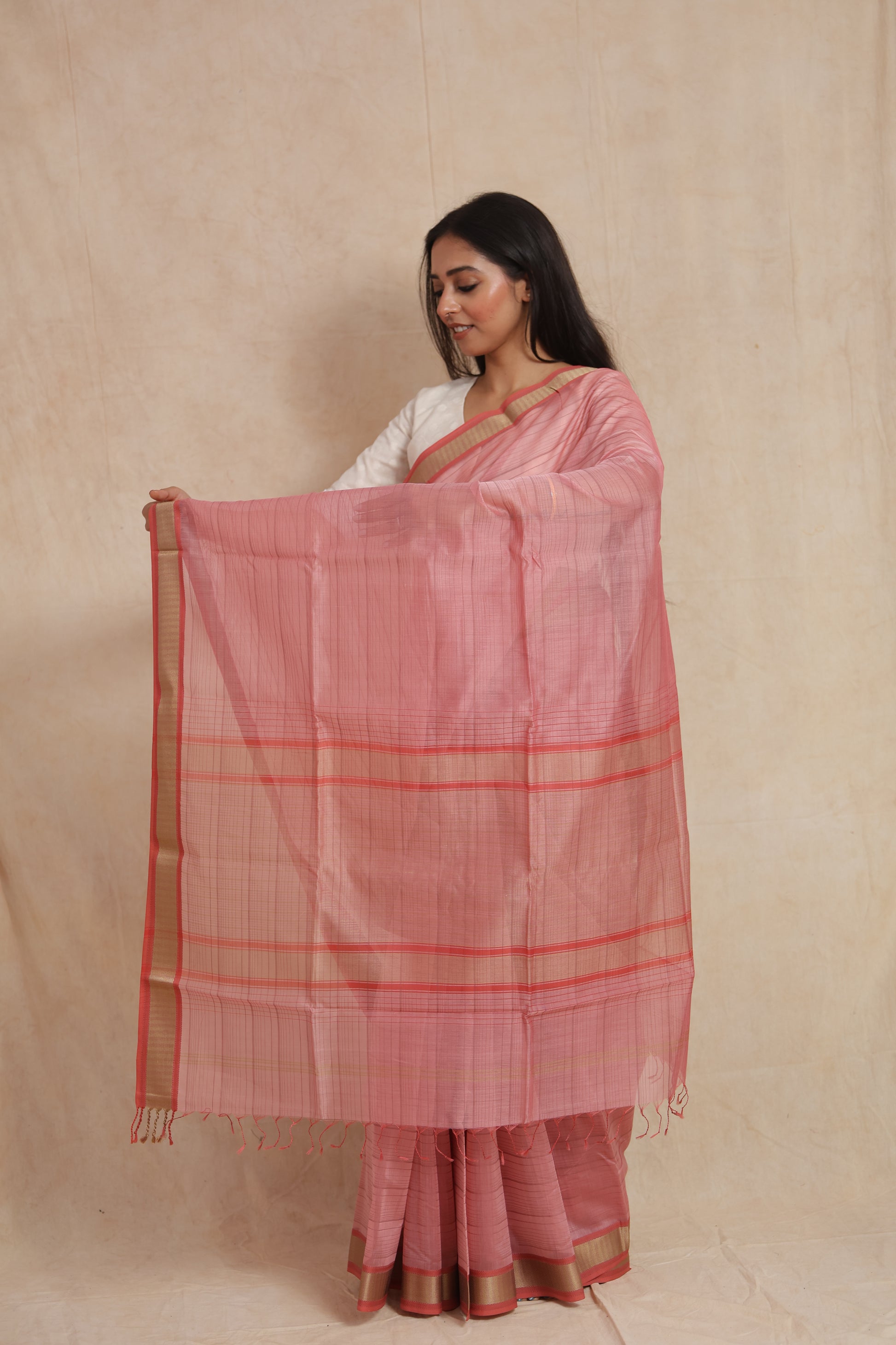 Model displaying the pallu of the blush pink Maheshwari cotton saree with delicate striped weaving and a refined gold border.