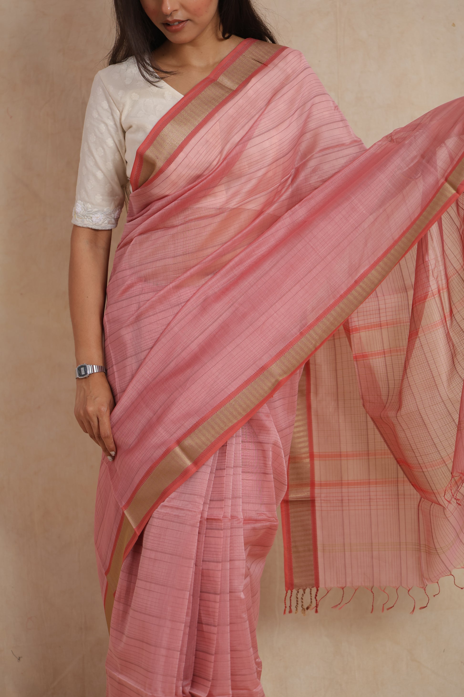 Close-up of the blush pink Maheshwari cotton saree highlighting the fine striped texture and elegant gold border.