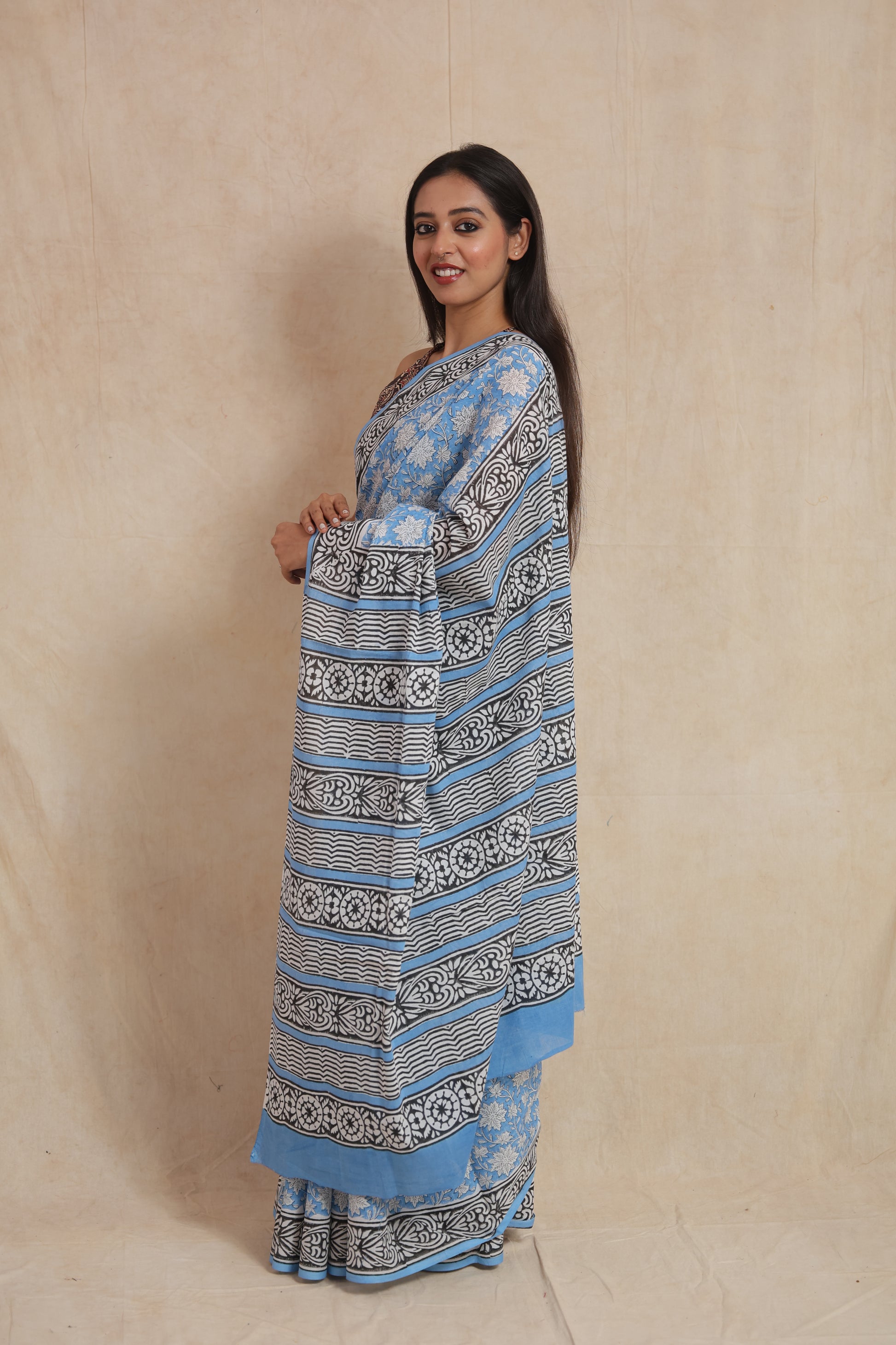 Side view of a sky blue cotton saree with floral print body and striped black and white pallu.