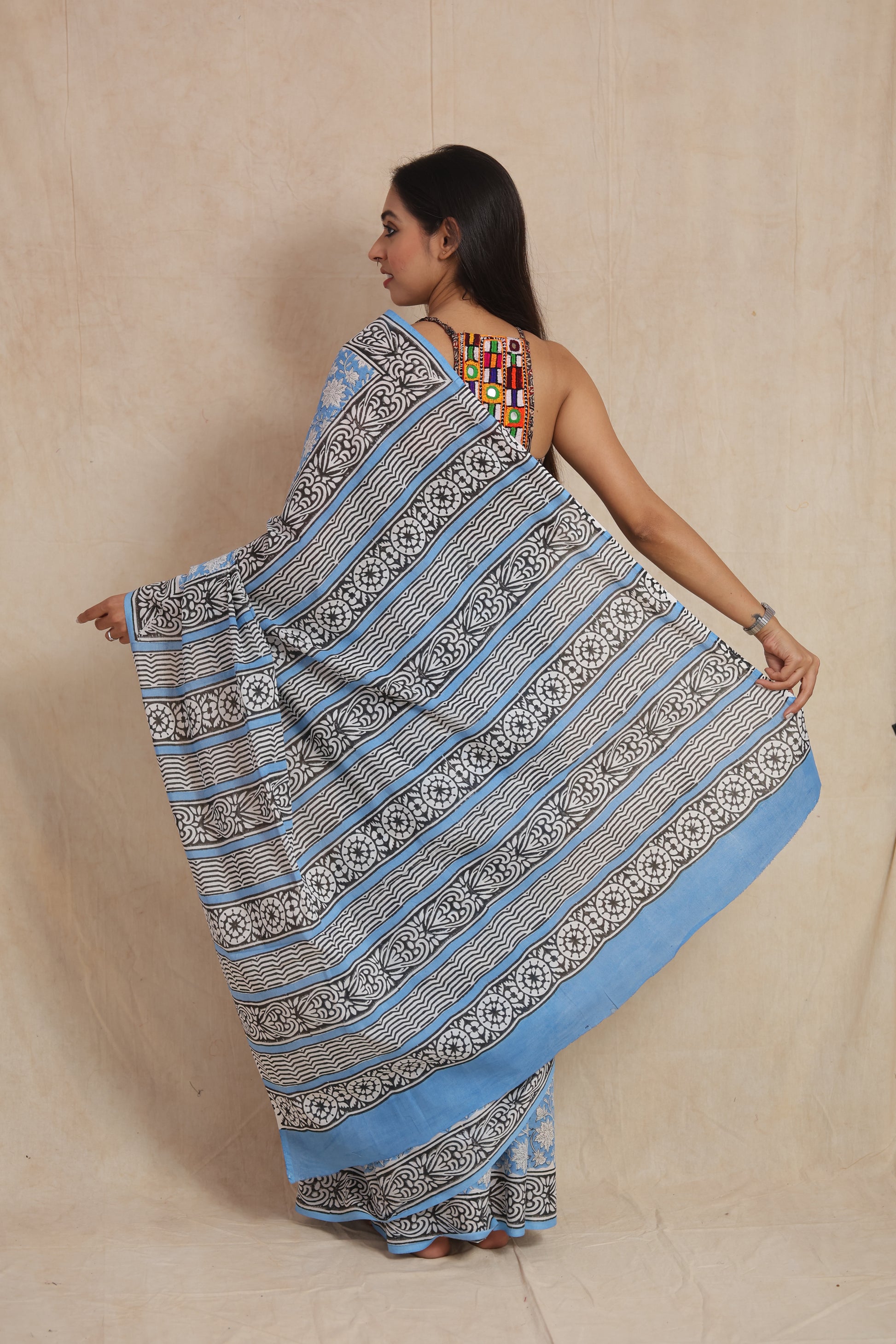 Back view of a sky blue cotton saree showcasing the striped pallu and contrasting printed border.