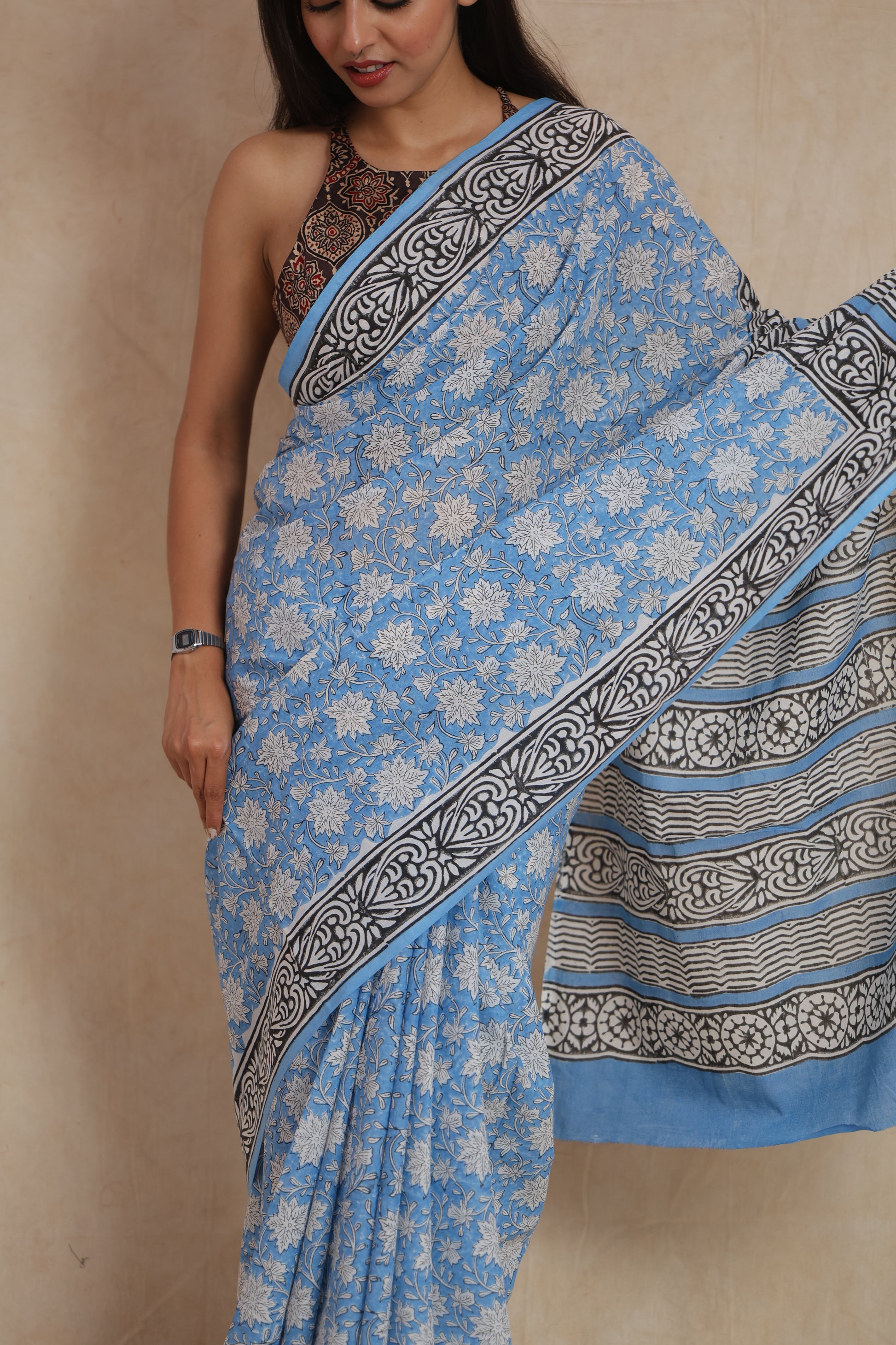 Close-up of the sky blue cotton saree highlighting intricate white floral prints and the decorative border.