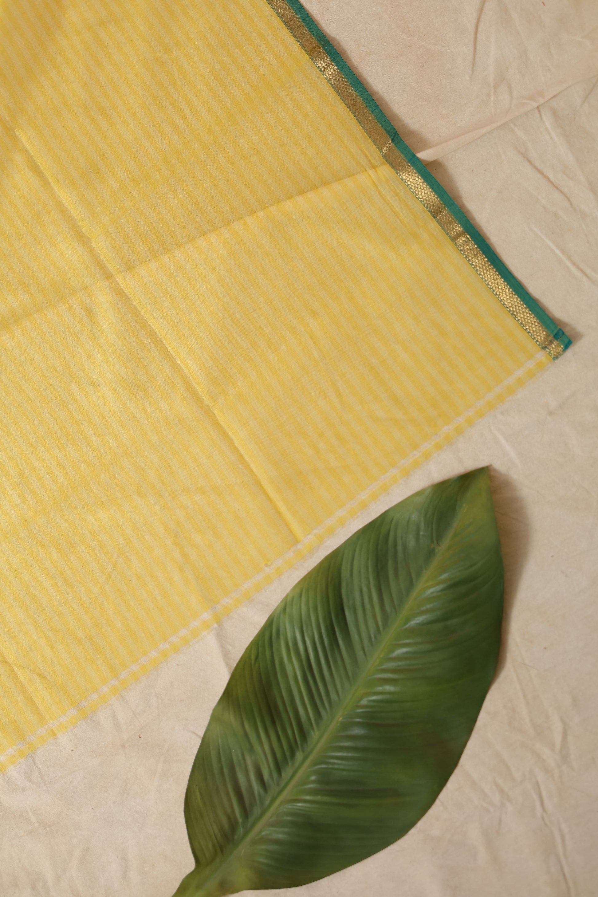 Flat lay detail of sunshine yellow Maheshwari handloom silk saree fabric and border
