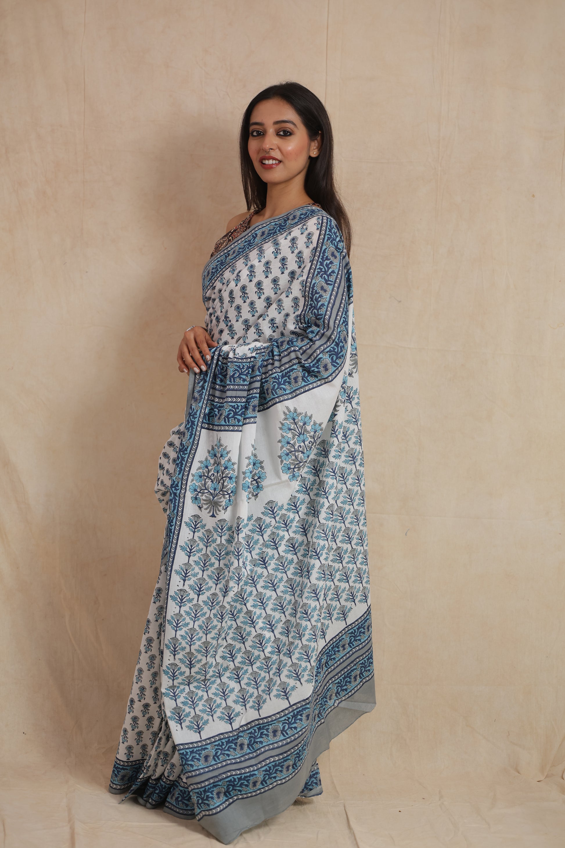 Side view of a white cotton saree featuring blue floral prints and an elegant blue printed border.