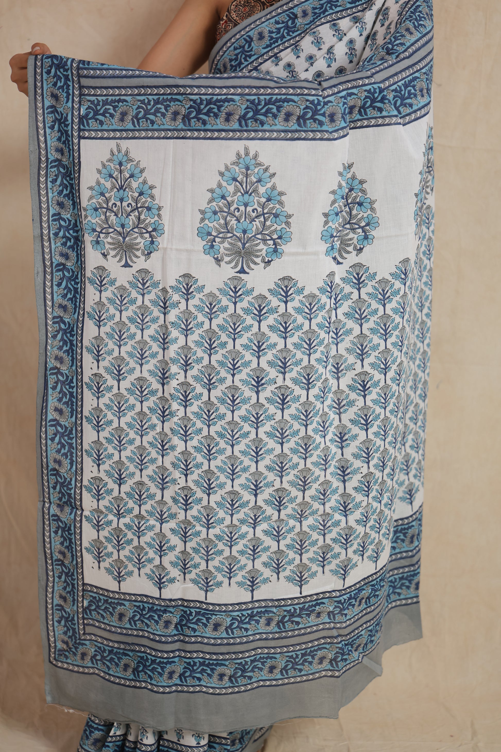 Detailed view of the white cotton saree pallu with blue floral motifs and decorative printed border.