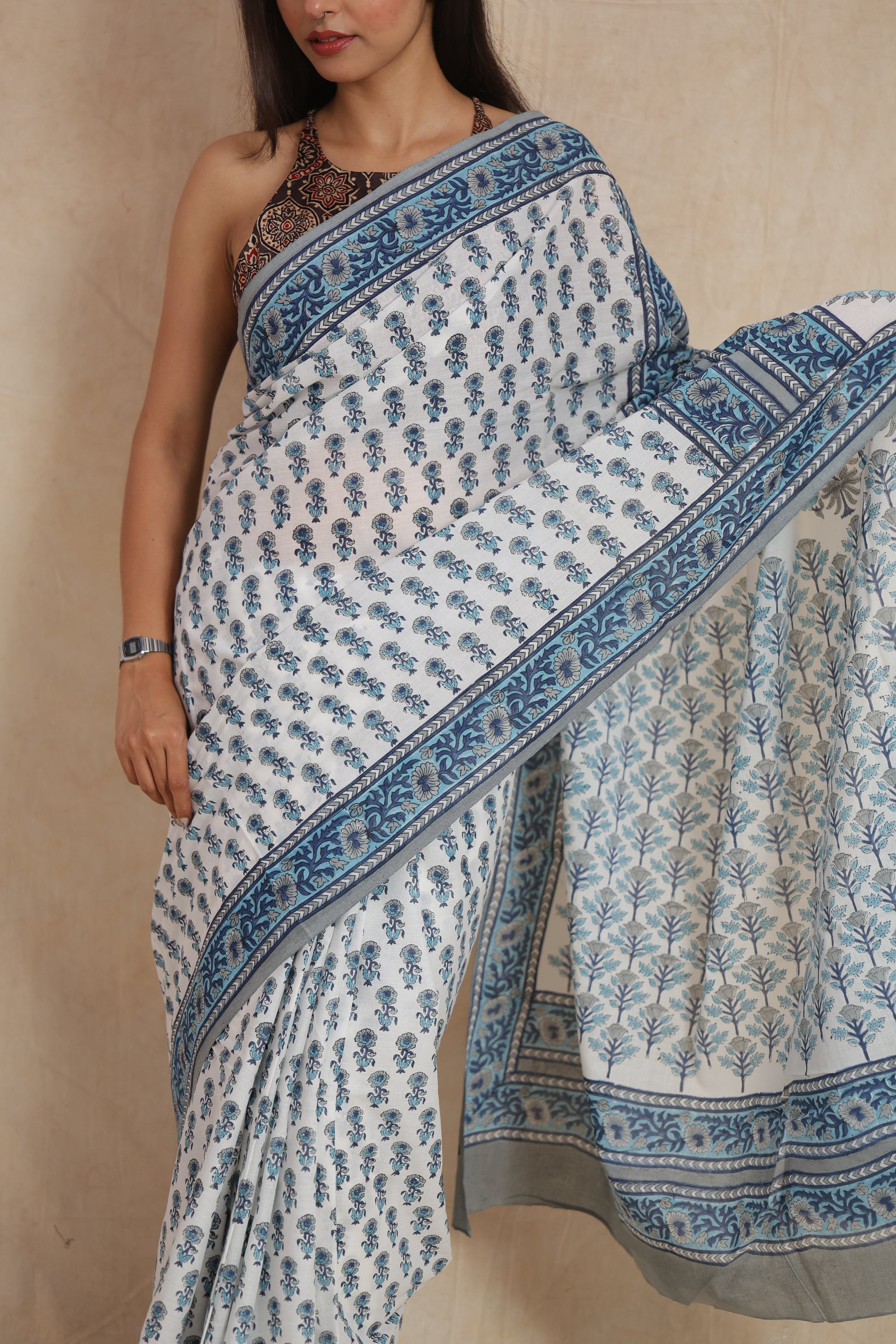 Close-up of the white cotton saree highlighting the blue floral print, border, and soft cotton texture.