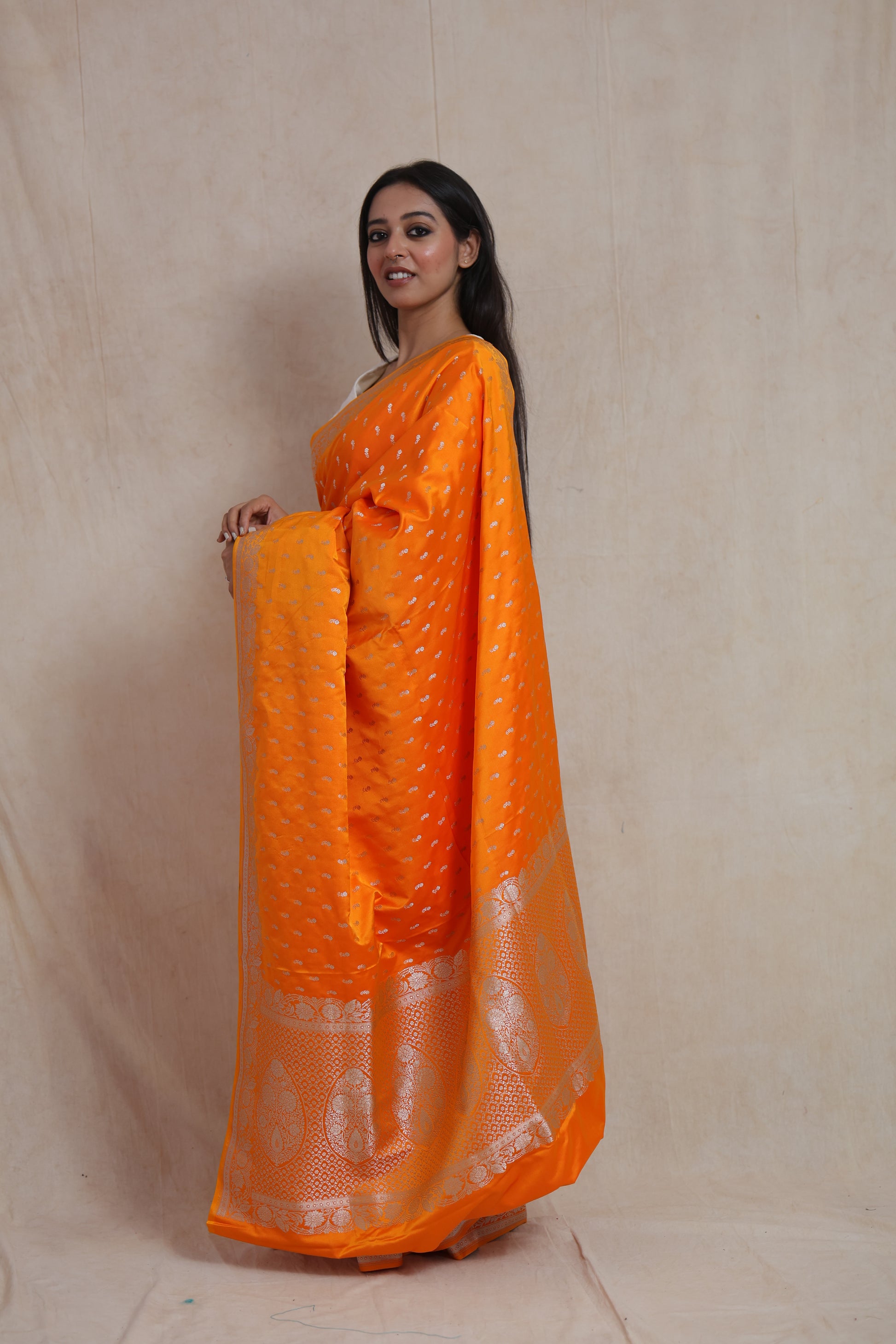 Side profile of orange Banarasi silk saree showcasing elegant woven motifs and border