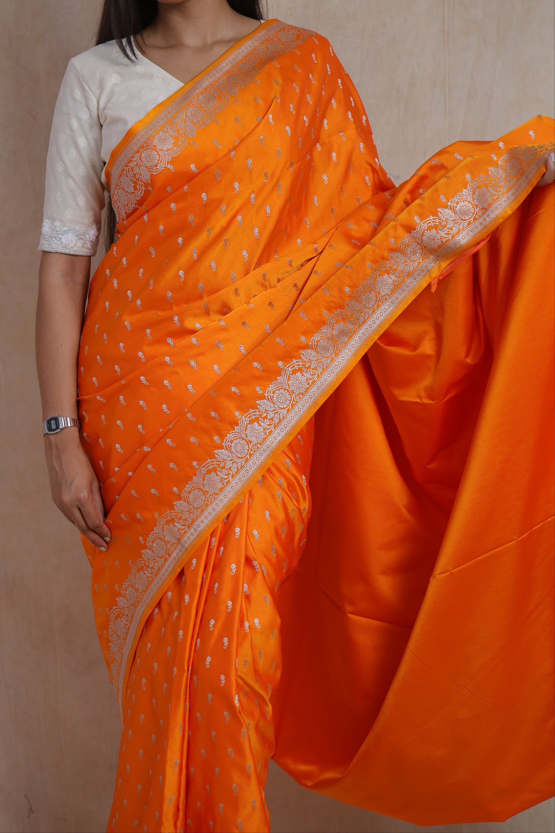 Close-up of orange Banarasi silk saree with silver buttas and floral woven border