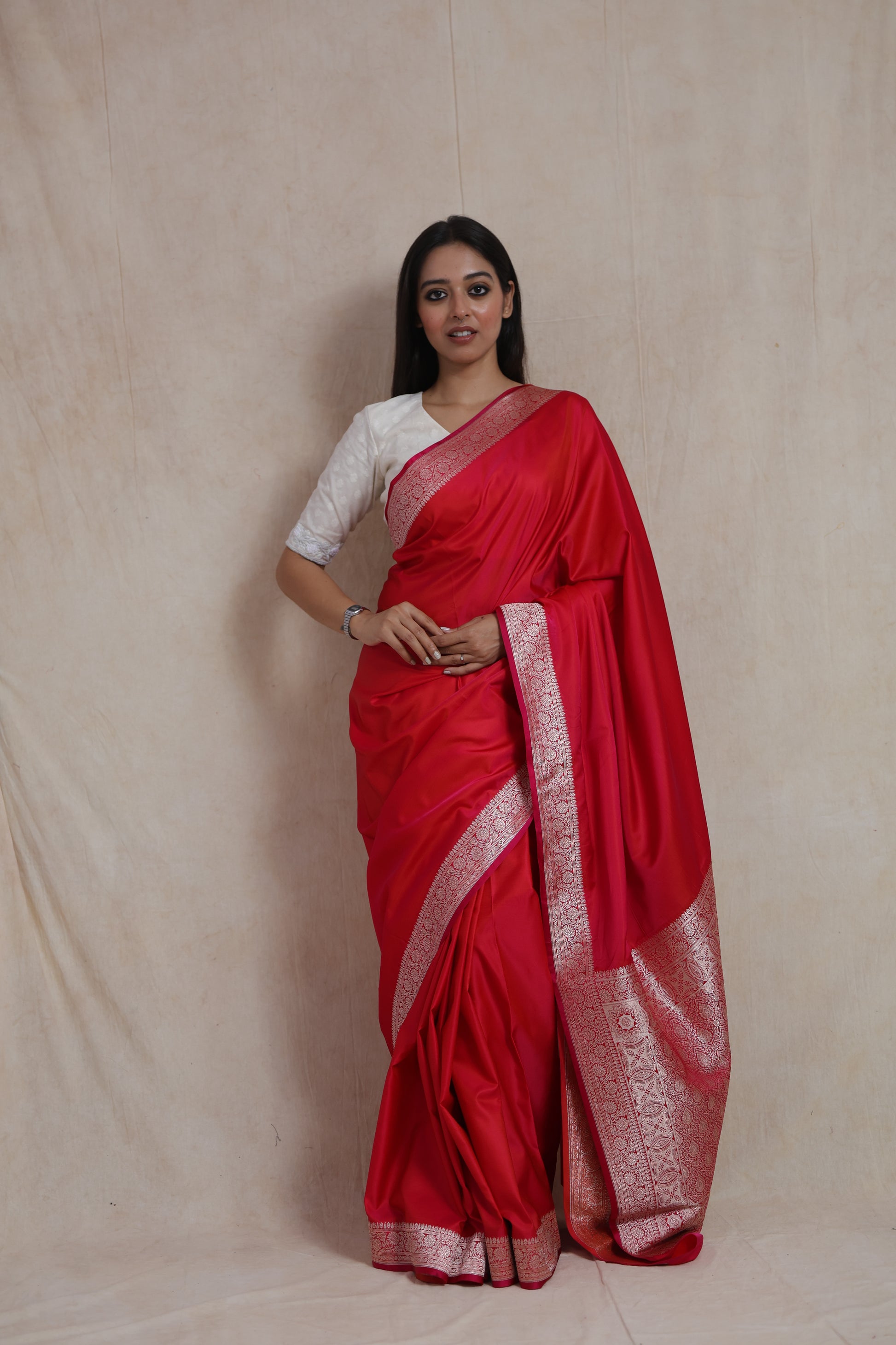 Model wearing ruby red Banarasi silk saree with silver zari woven border