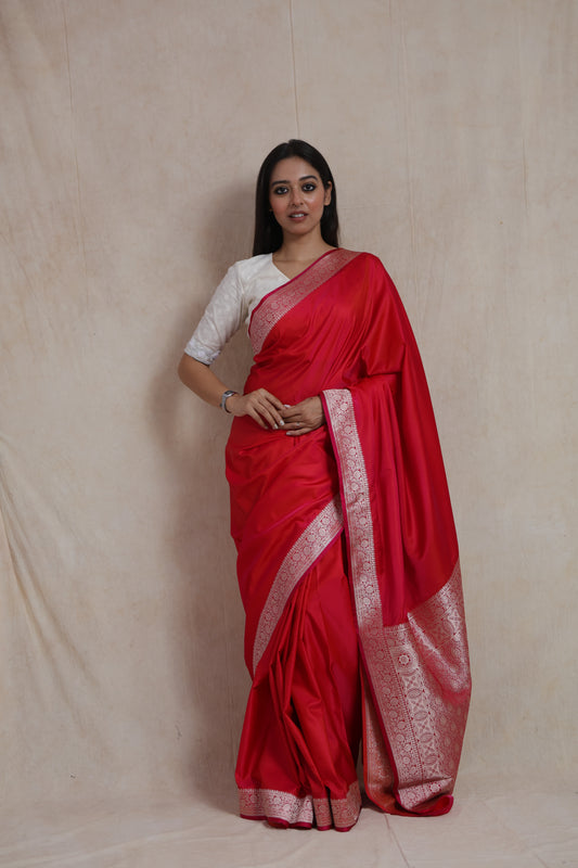 Model wearing ruby red Banarasi silk saree with silver zari woven border