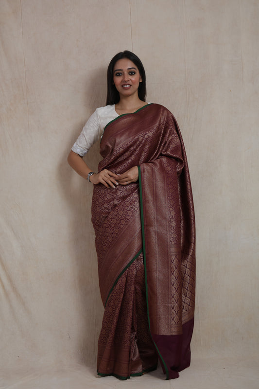 Model wearing wine purple Banarasi silk saree with antique gold floral weaving