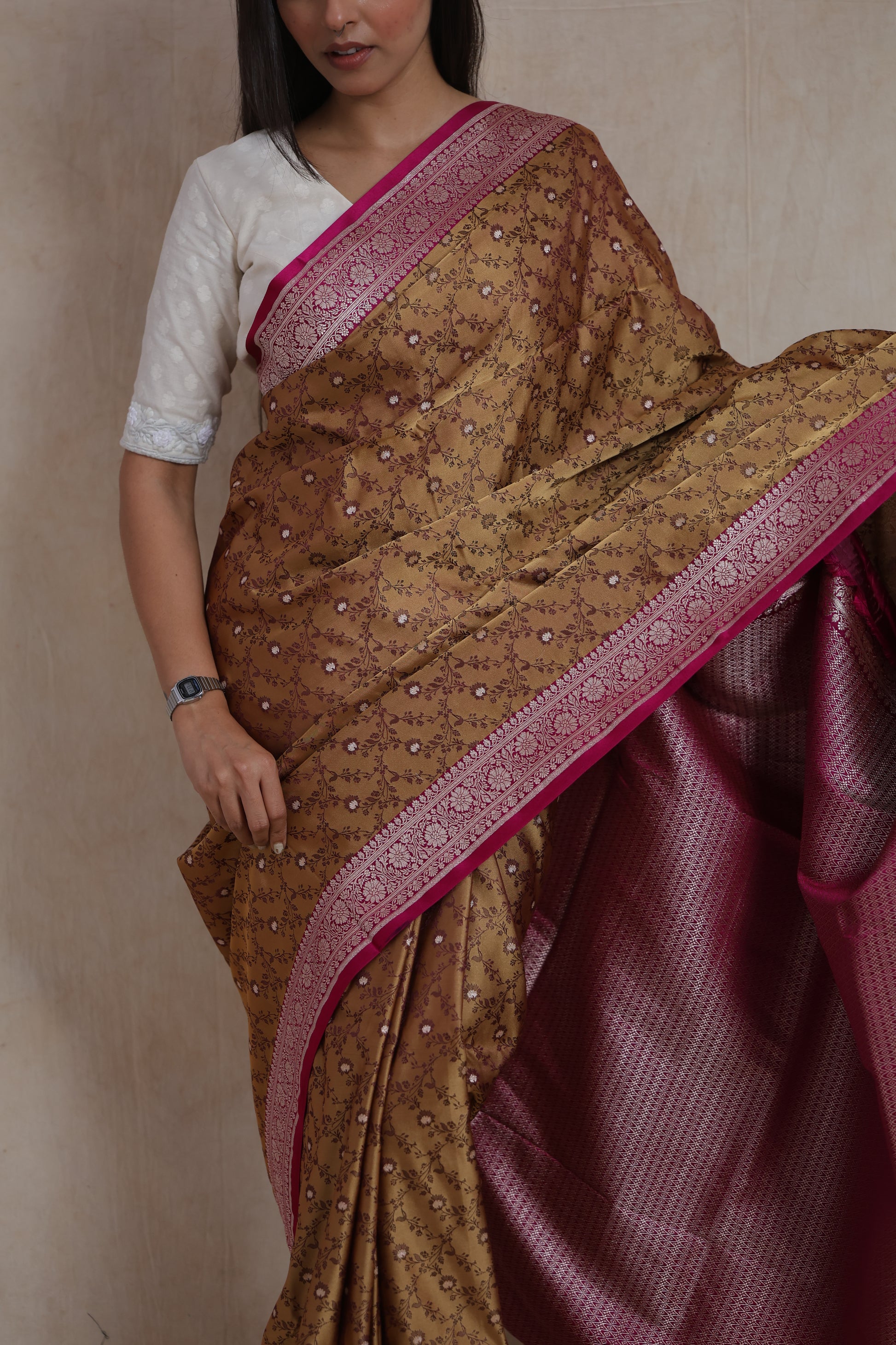 Close-up of golden beige Banarasi silk saree featuring floral woven motifs and pink border