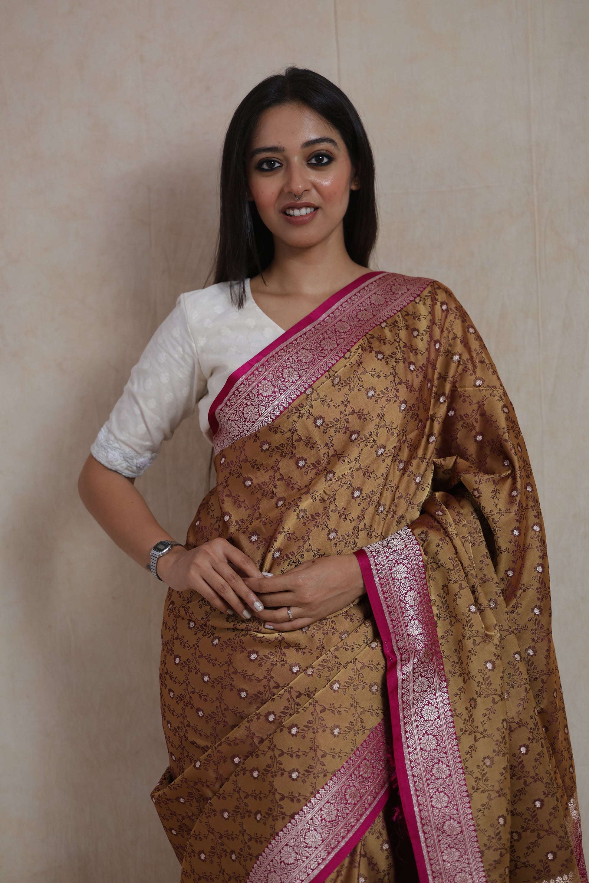 Close-up of golden beige Banarasi silk saree featuring floral woven motifs and pink border
