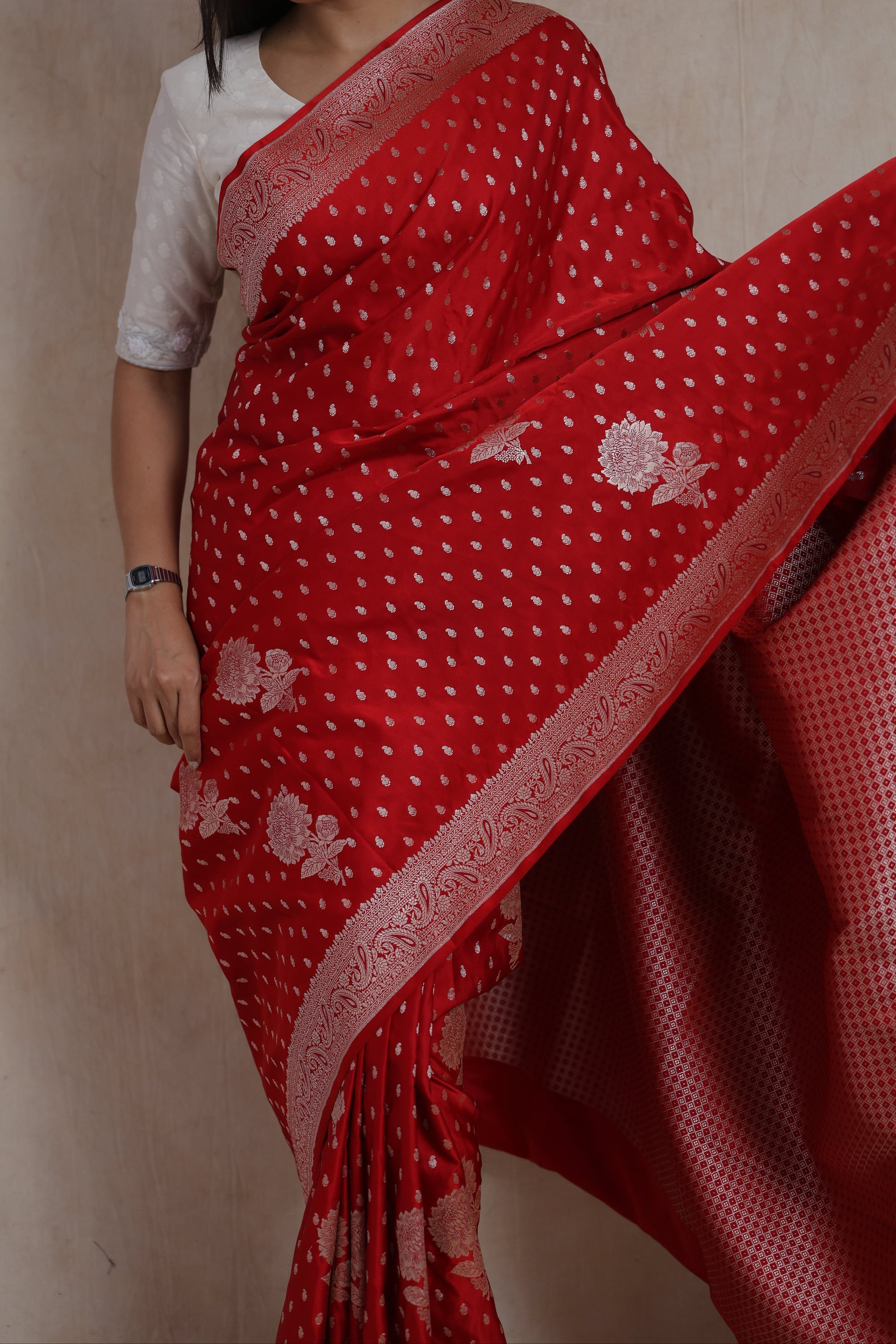 Close-up of red Banarasi art silk saree highlighting silver buttas and decorative woven border