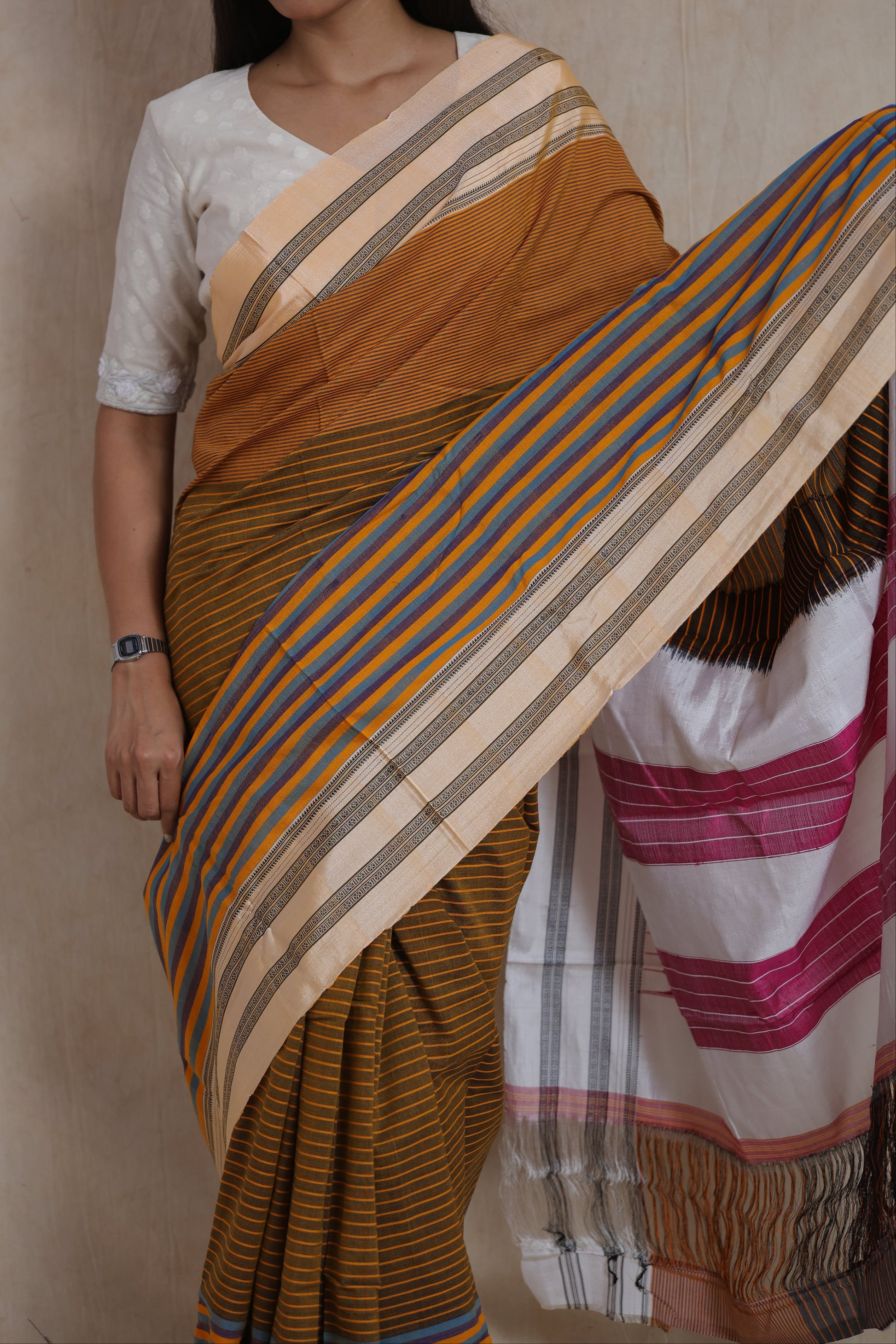 Front view of mustard brown Ilkal handloom cotton saree with multicolor striped pallu and traditional border