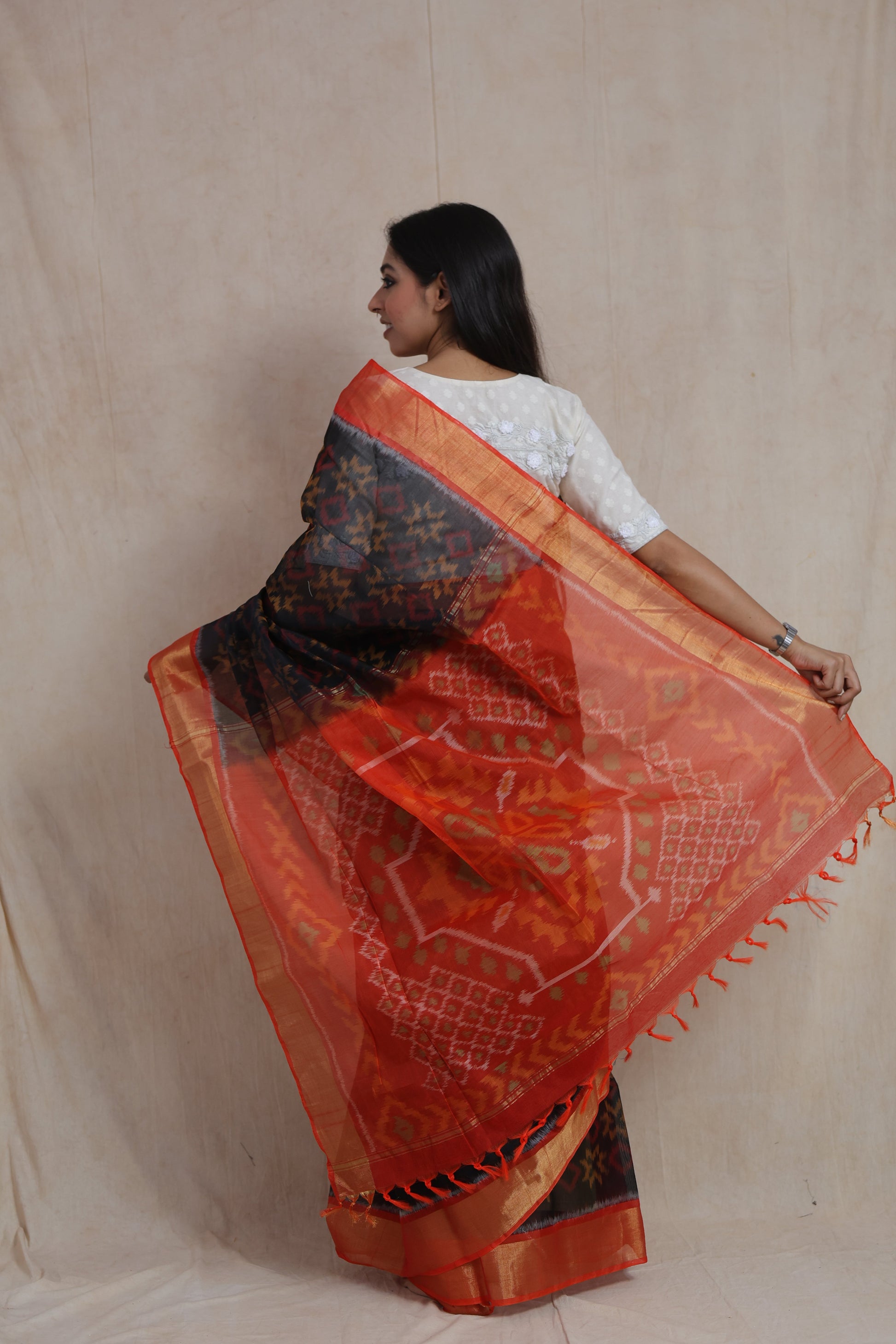 Back view of black Panchampali SICO saree with detailed orange ikat woven pallu and tassels
