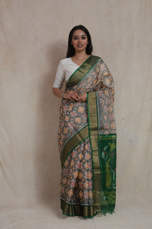 Front view of grey Pochampally SICO saree with emerald green border and traditional Ikat motifs.