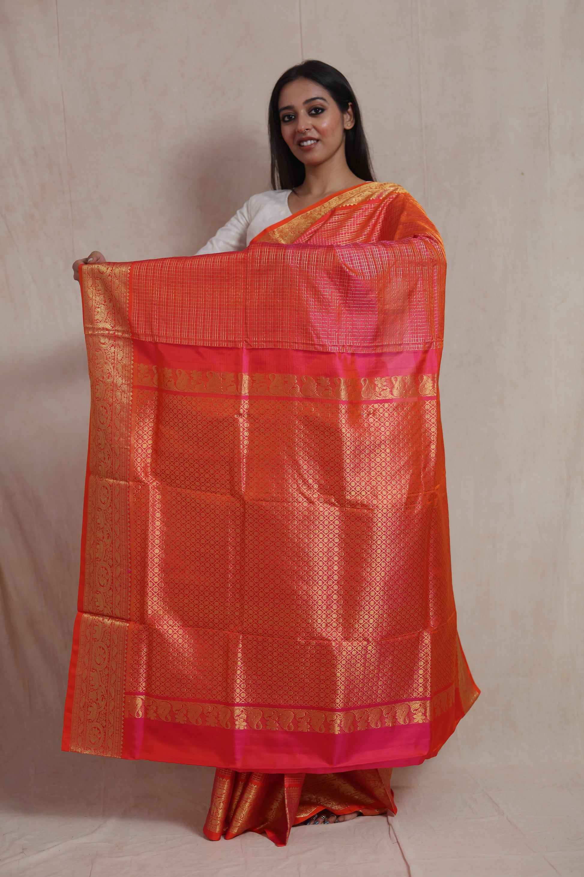 Model displaying the pallu of a Coral Orange Kanjivaram Silk  Saree with pink contrast border