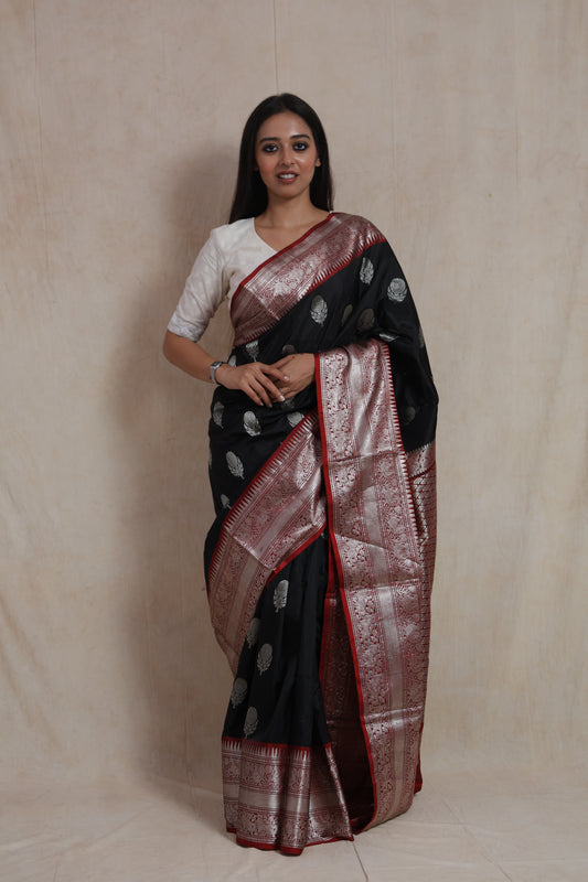 Front view of a black Kanjivaram silk saree featuring silver woven buttas, an ornate border, and a rich woven pallu.