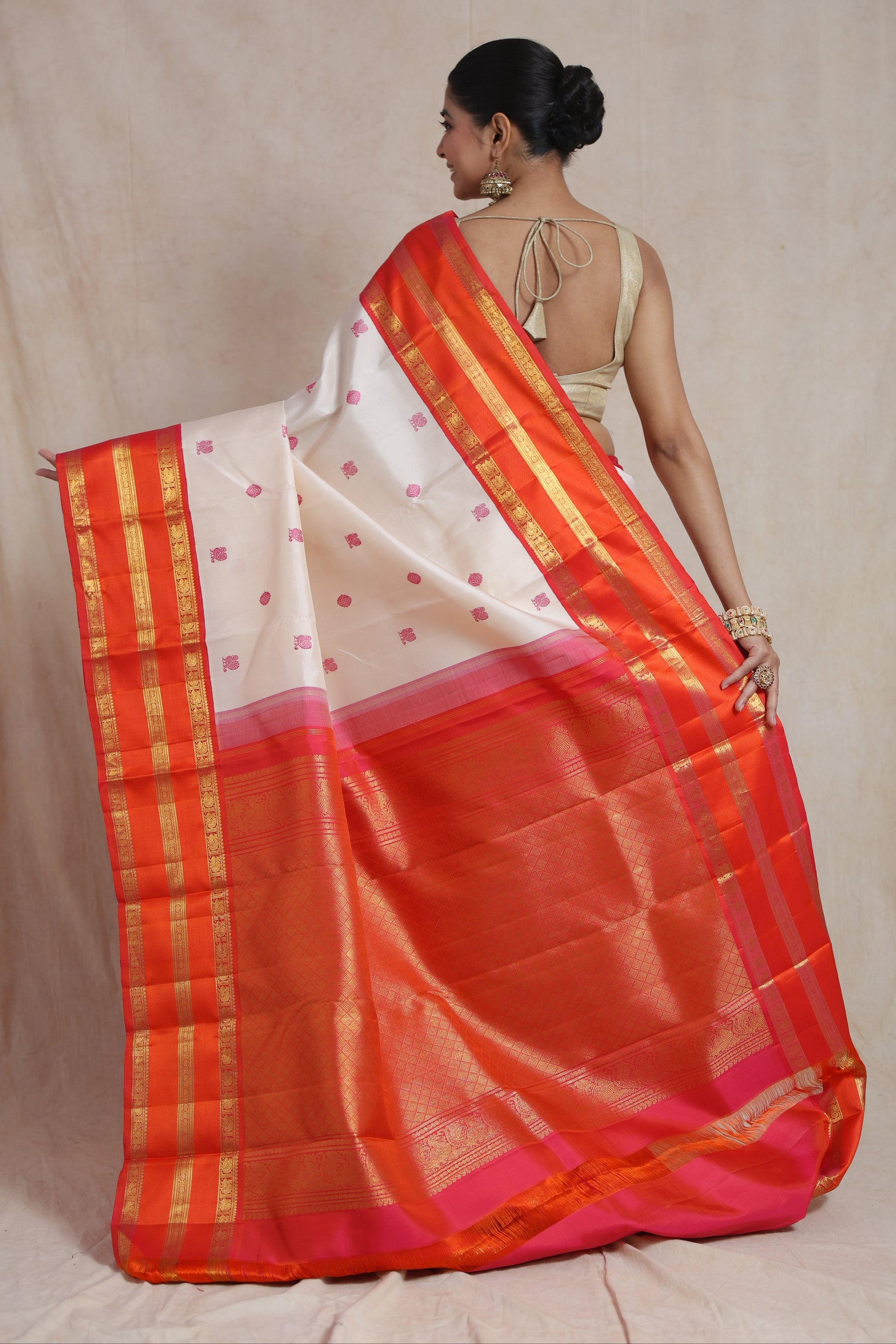 Back view of ivory white Kanjivaram silk saree highlighting the grand coral orange pallu