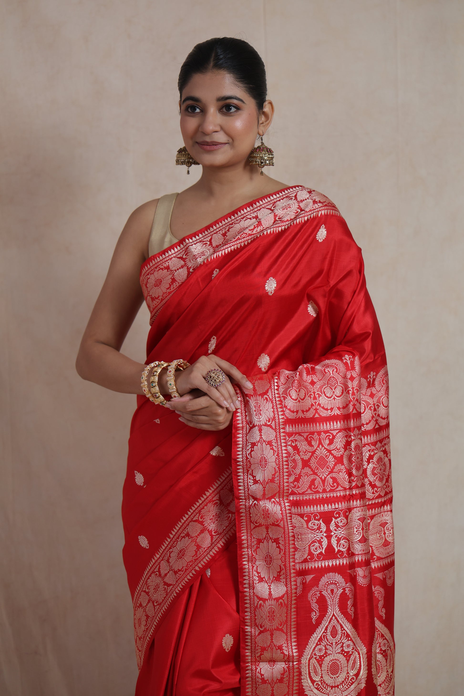 Portrait view of a model wearing a royal red Banarasi silk saree with intricate woven buttas and an ornate traditional pallu.