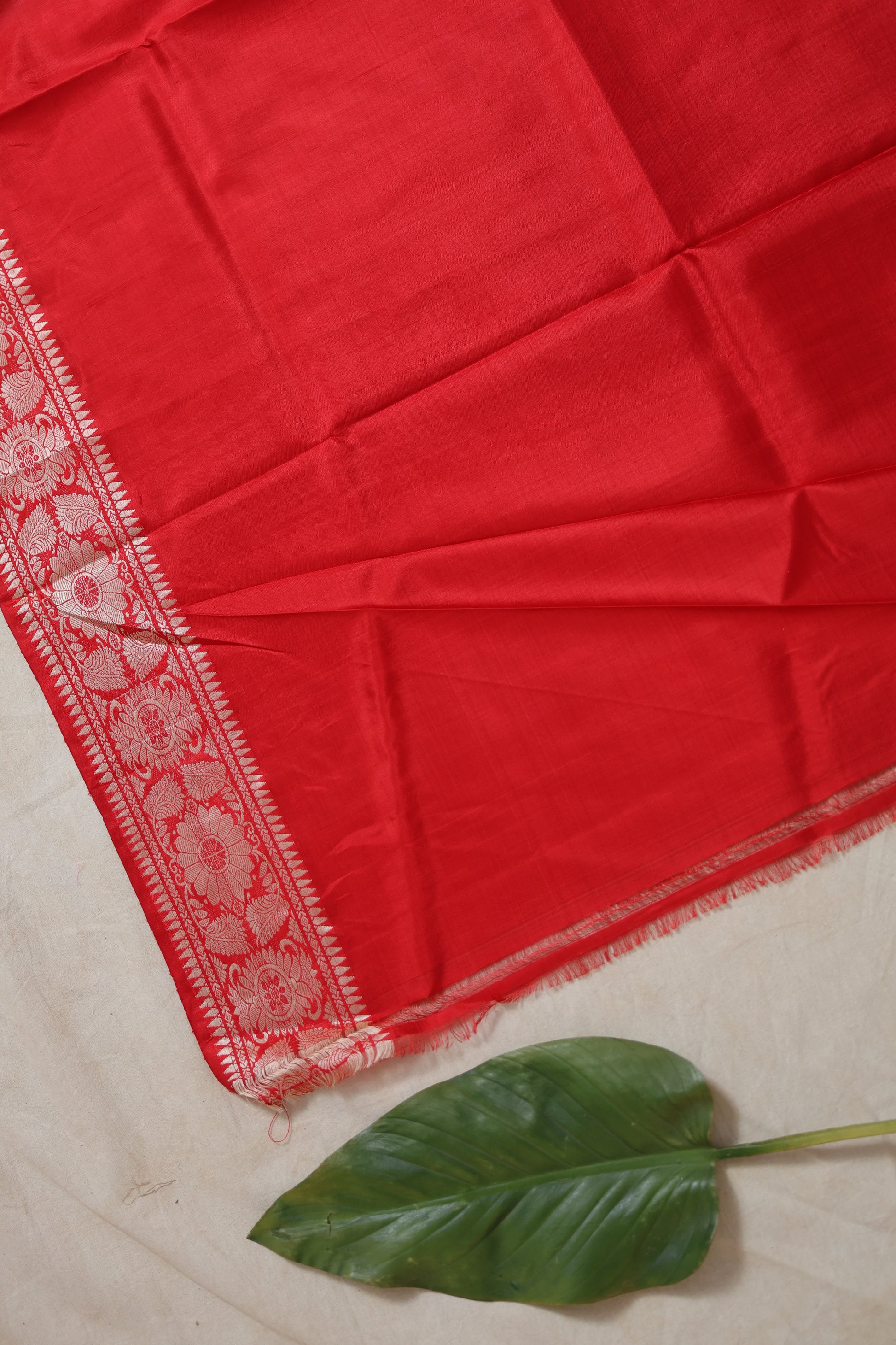 Flat-lay view of the royal red Banarasi silk saree displaying its woven border, smooth silk body, and traditional pallu.