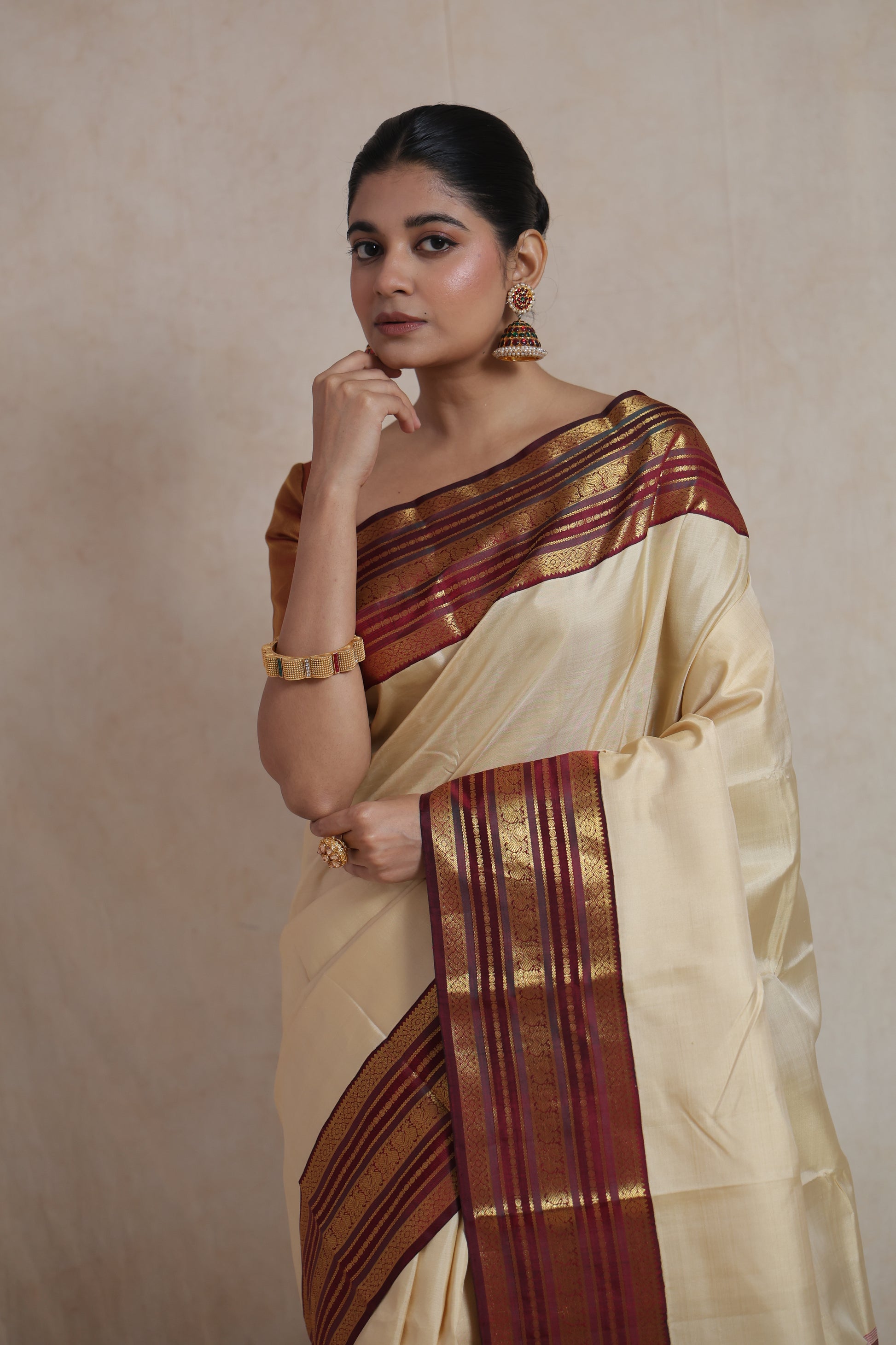 Close-up view of ivory Kanjivaram silk saree featuring maroon contrast border with intricate traditional weaving