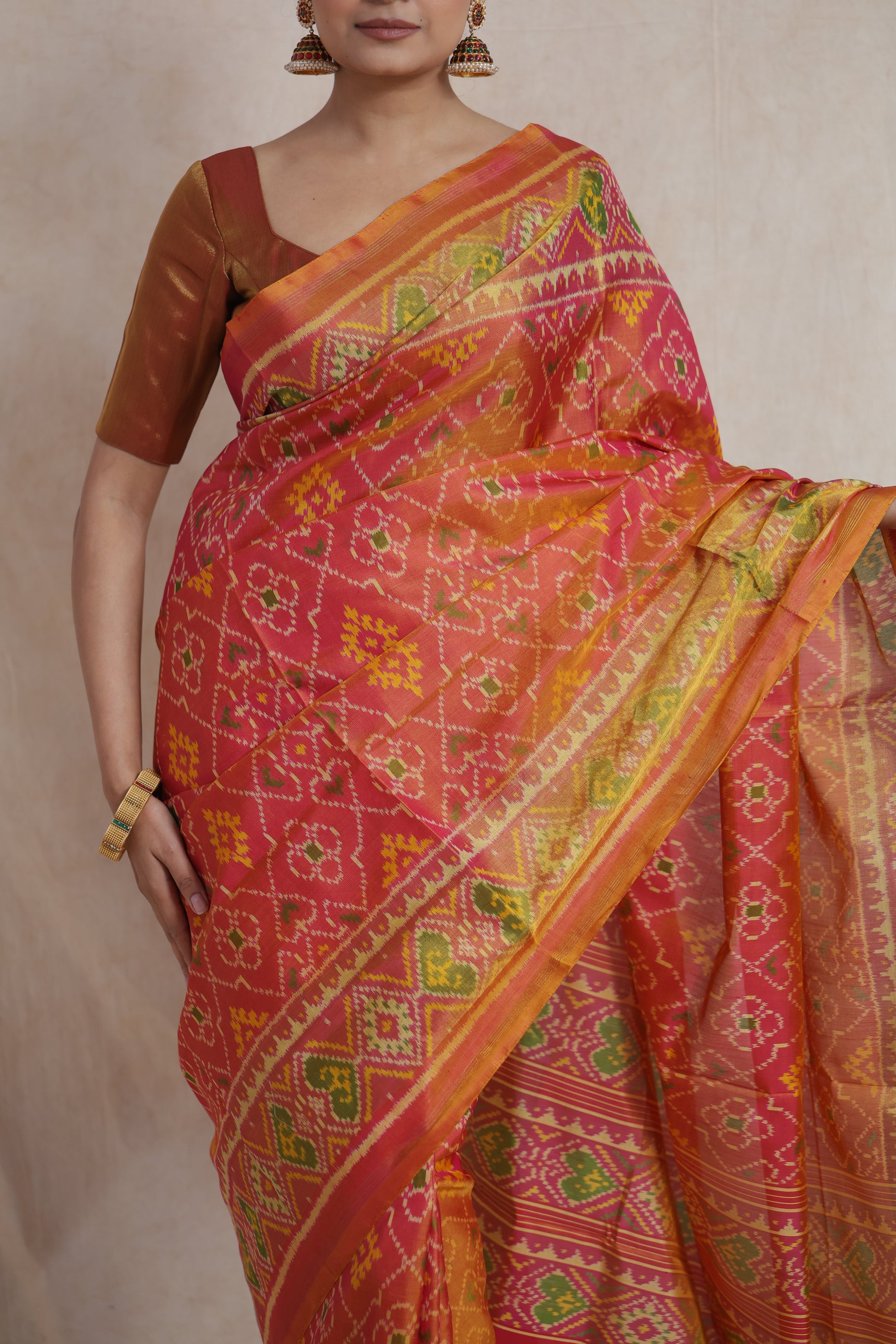Close-up of coral Patola handloom silk saree featuring intricate geometric and floral ikat patterns