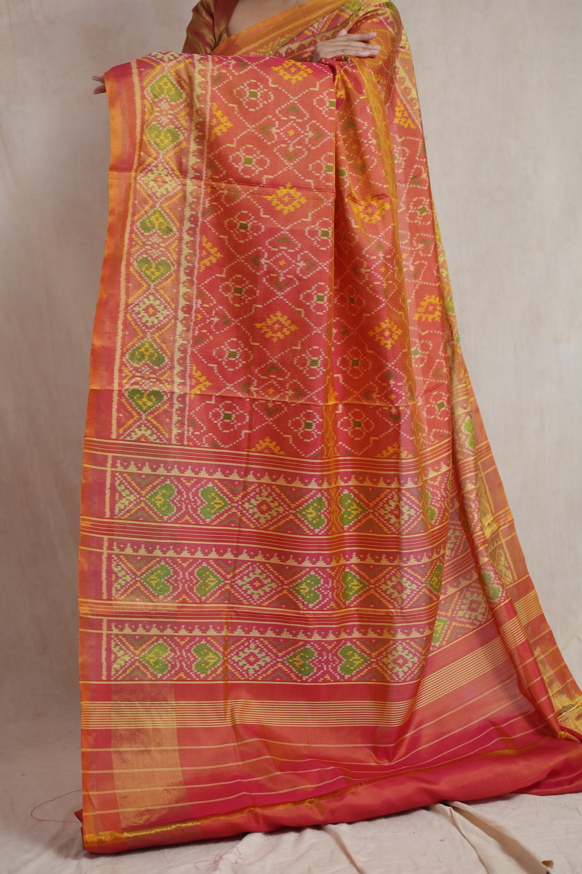 Detailed pallu of coral Patola silk saree showcasing traditional handwoven motifs and borders