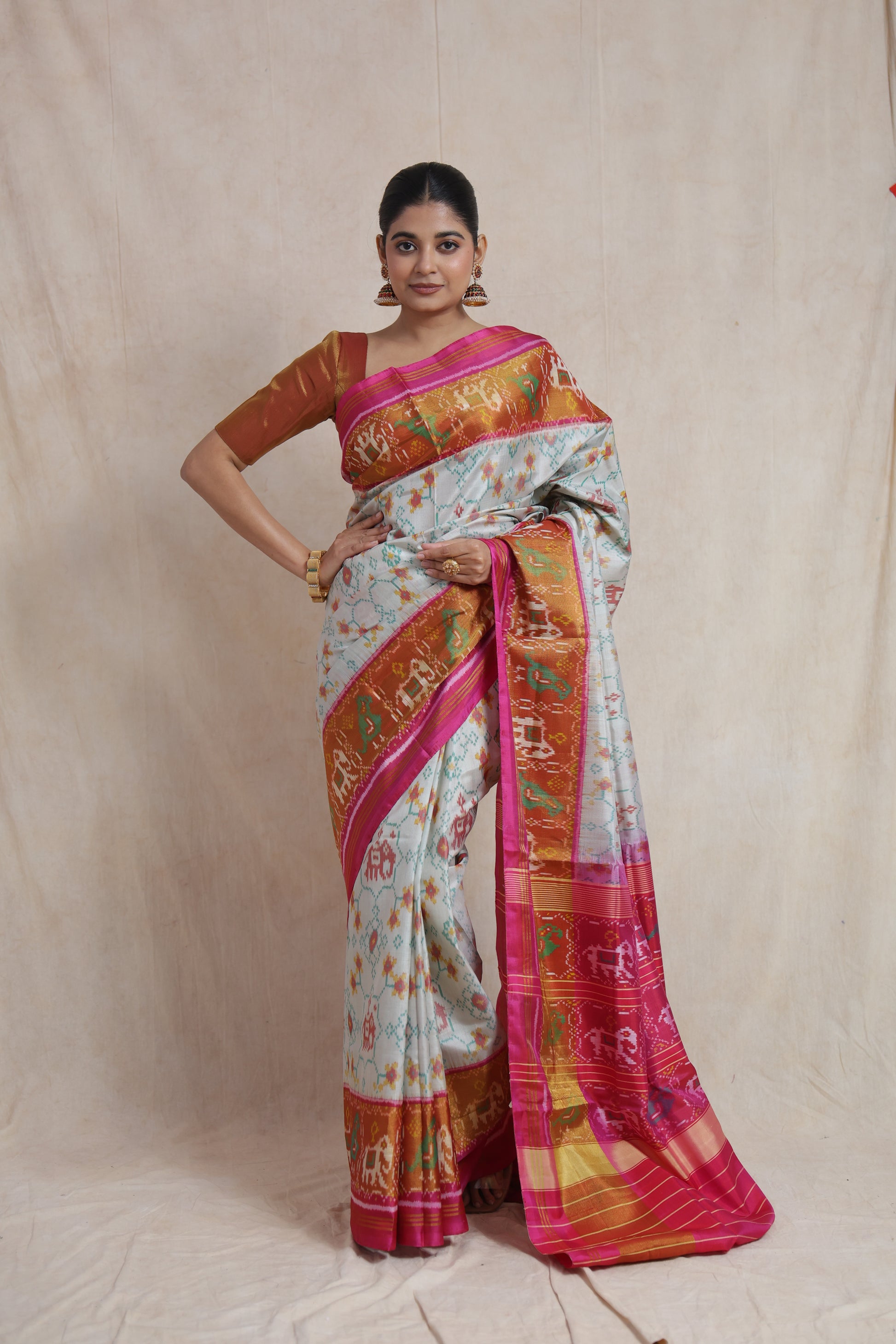 Model wearing ivory Patola silk saree with pink border and traditional Ikat motifs