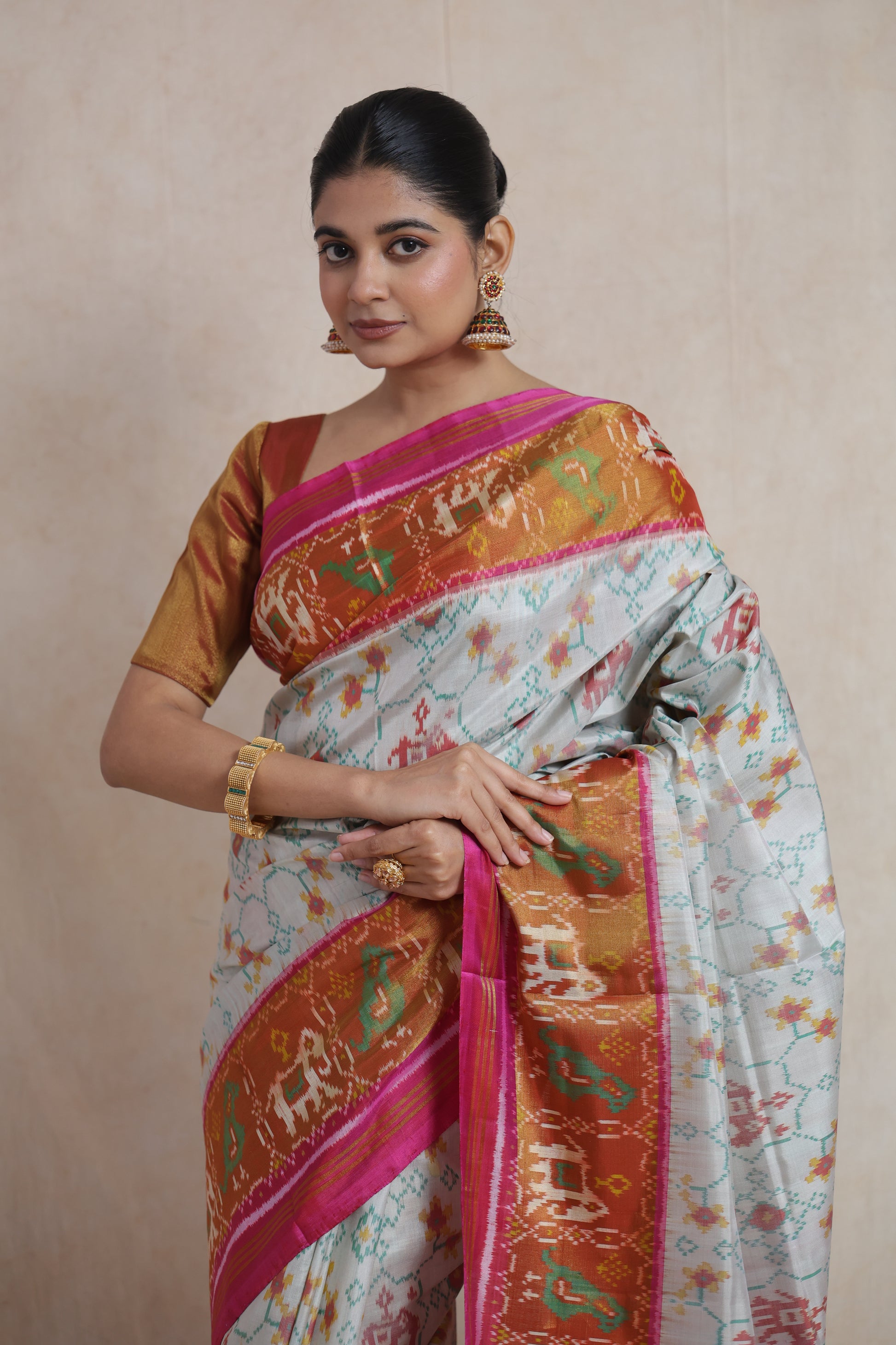 Detailed drape of ivory Patola silk saree with pink and antique gold woven border