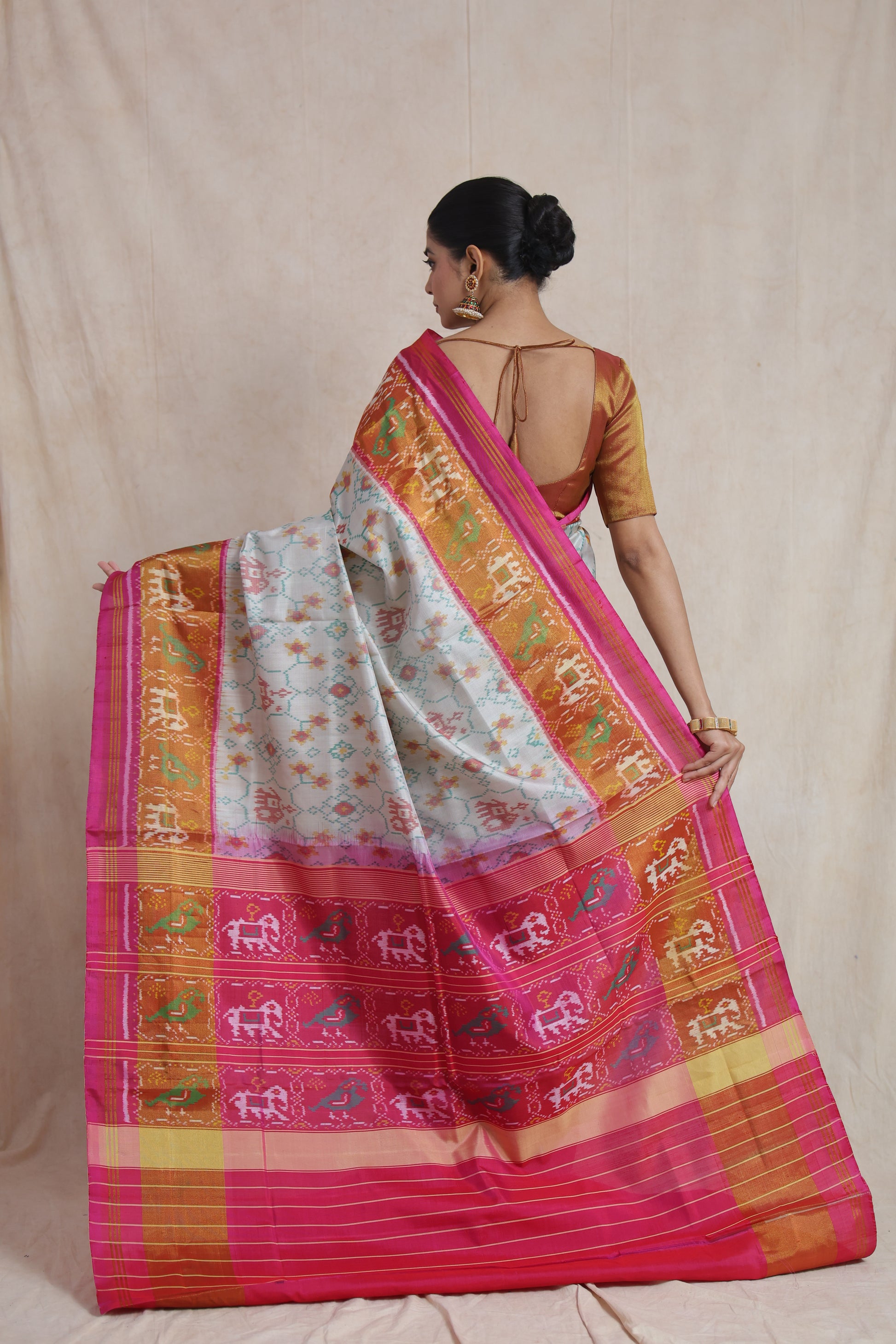 Back view displaying the rich pallu and woven border of the ivory Patola silk saree