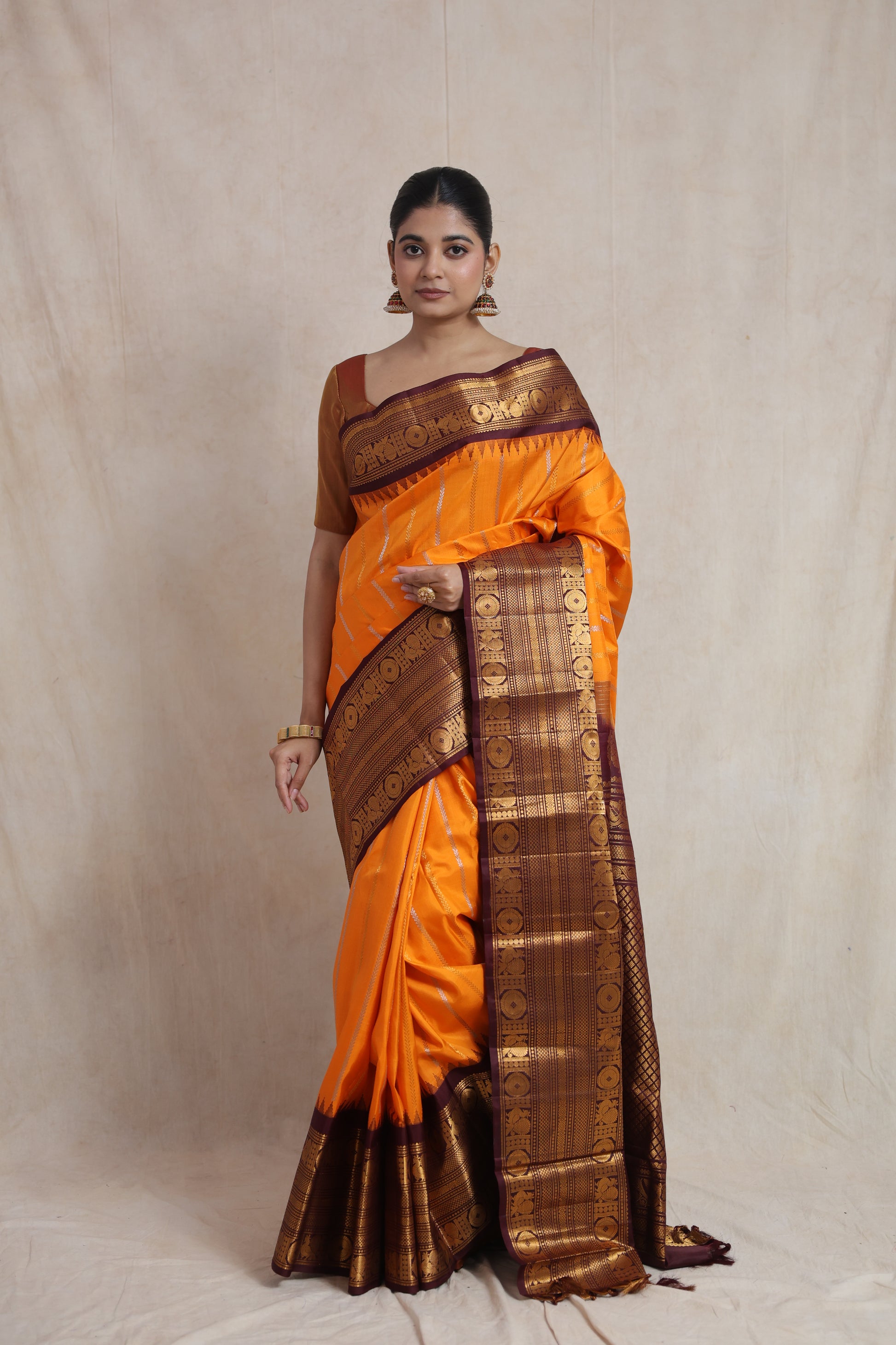 Front view of a burnt orange Gadwal silk saree with a deep brown woven border and elegant traditional pallu.